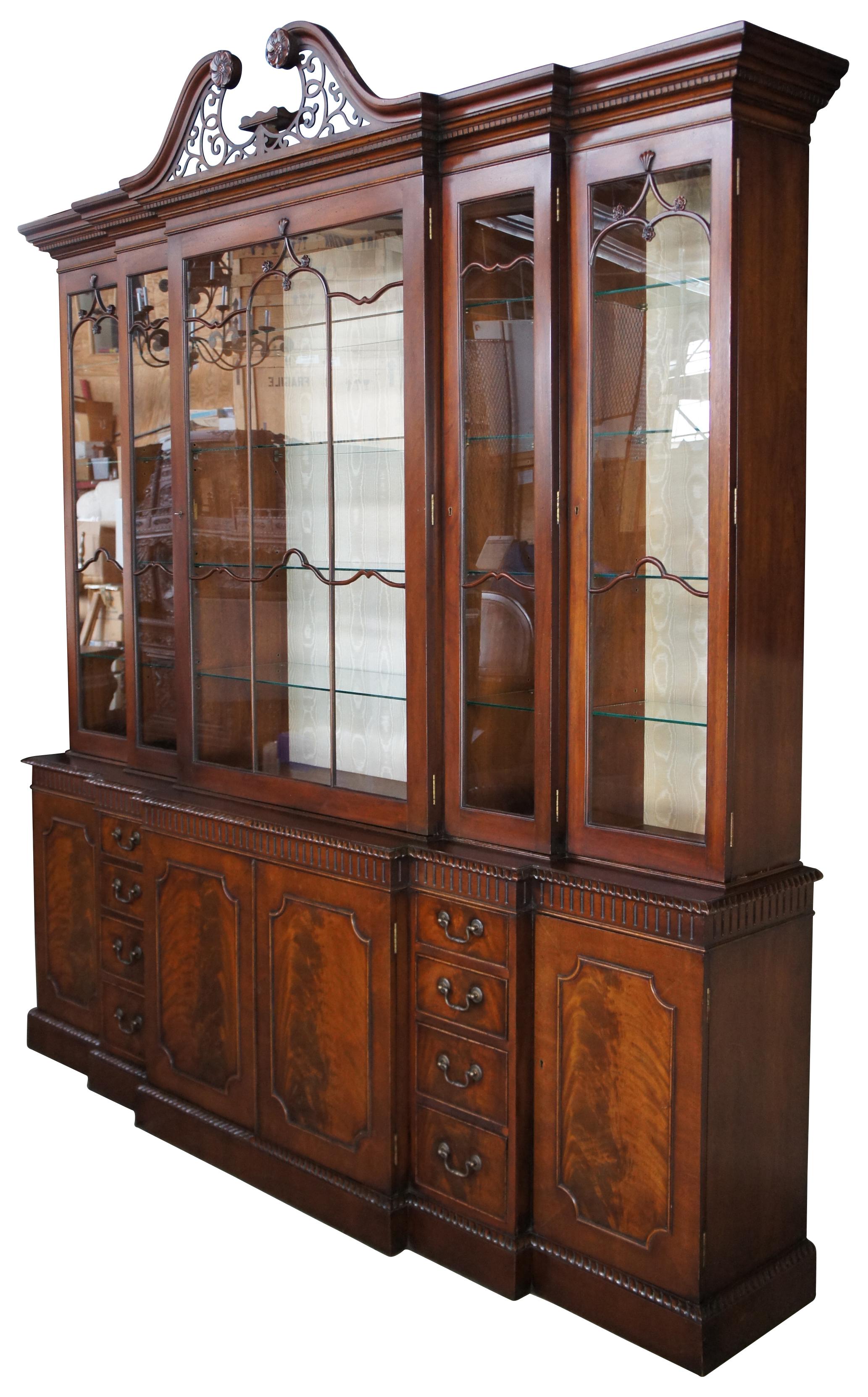 Monumental Chippendale double breakfront, circa 1880s. Made from mahogany with a large and elegant upper illuminated display section. Includes four adjustable shelves, a silk backing, dentil carved molding and a beautiful open pediment fashioning