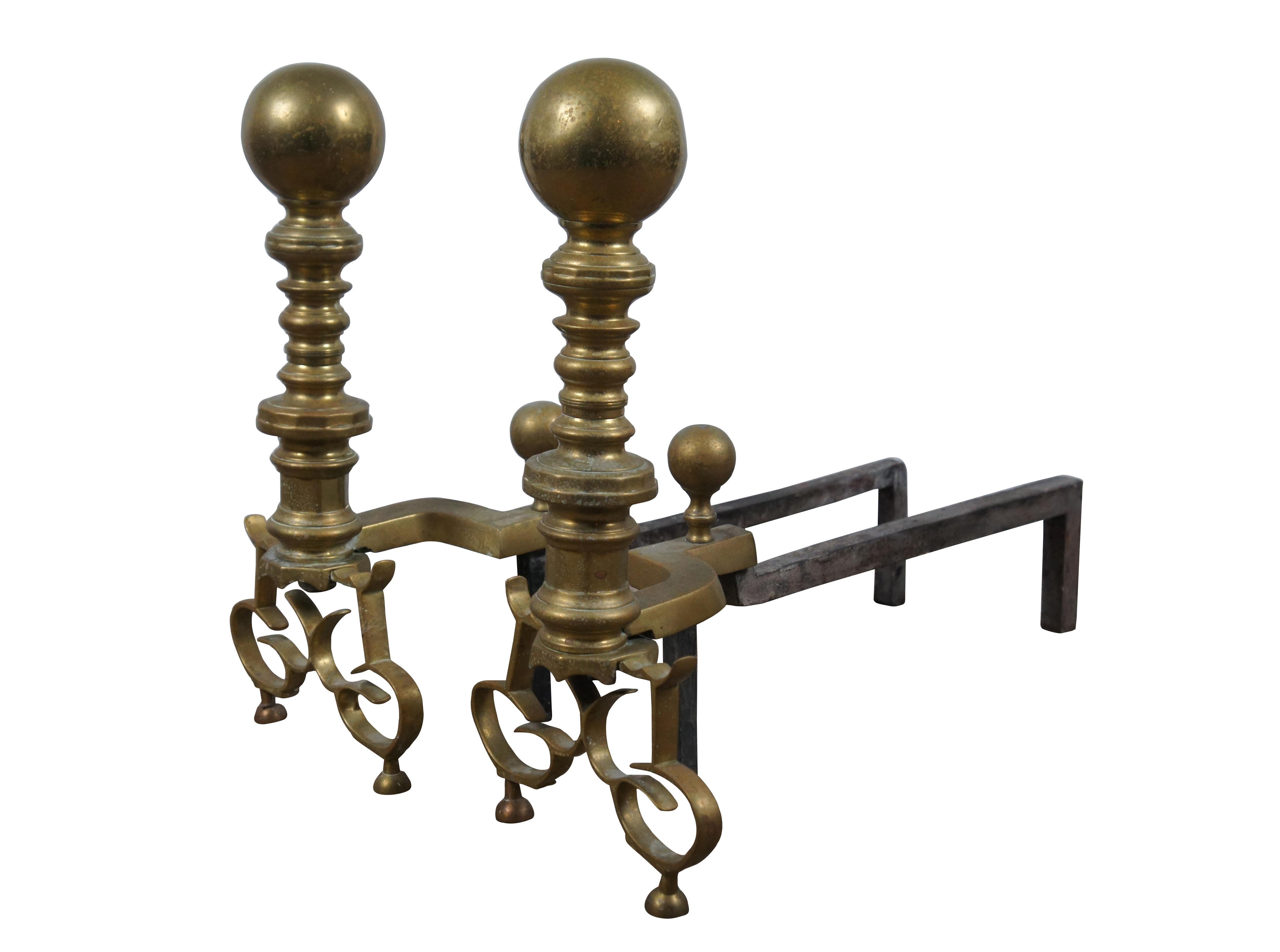 Pair of antique Georgian brass and iron andirons / fire dogs featuring cannonball tops on turned baluster pillars with ornate delicate scrolled feet.

Dimensions:
9.25