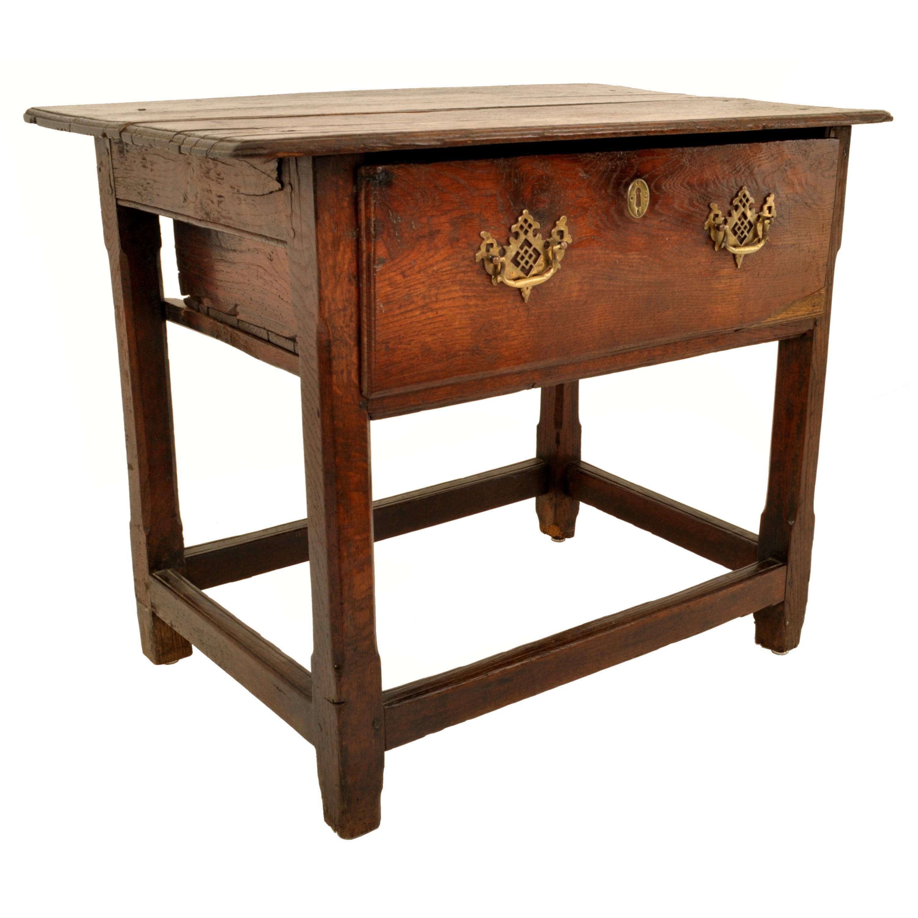 Antique George II oak tavern/side table, circa 1760.
The table having an overhanging top, with a single deep drawer to the center with pierced 'batwing' brasses, the table raised on chamfered legs and joined at the base with a stretcher on each