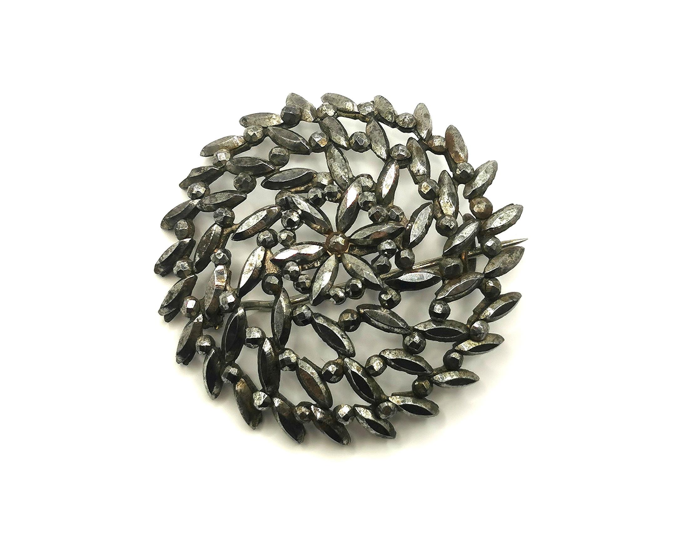 A beautiful antique late Georgian era cut steel brooch.

This is a circular Starburst type brooch with a little forget me not flower to the centre.

It has an old c type clasp and pin fastener.

Cut steel rose to popularity in the 18th century