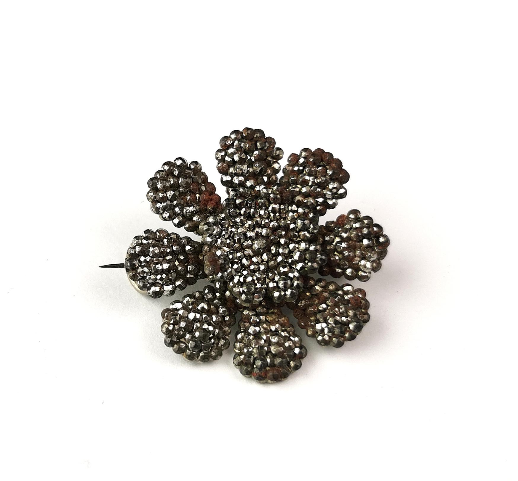 A beautiful antique late Georgian era cut steel flower brooch.

This is a circular floral brooch with carefully hand crafted individual petals all made from tiny cut steel cabochons, the brooch has a 3d effect to it with the layered petals.

It has