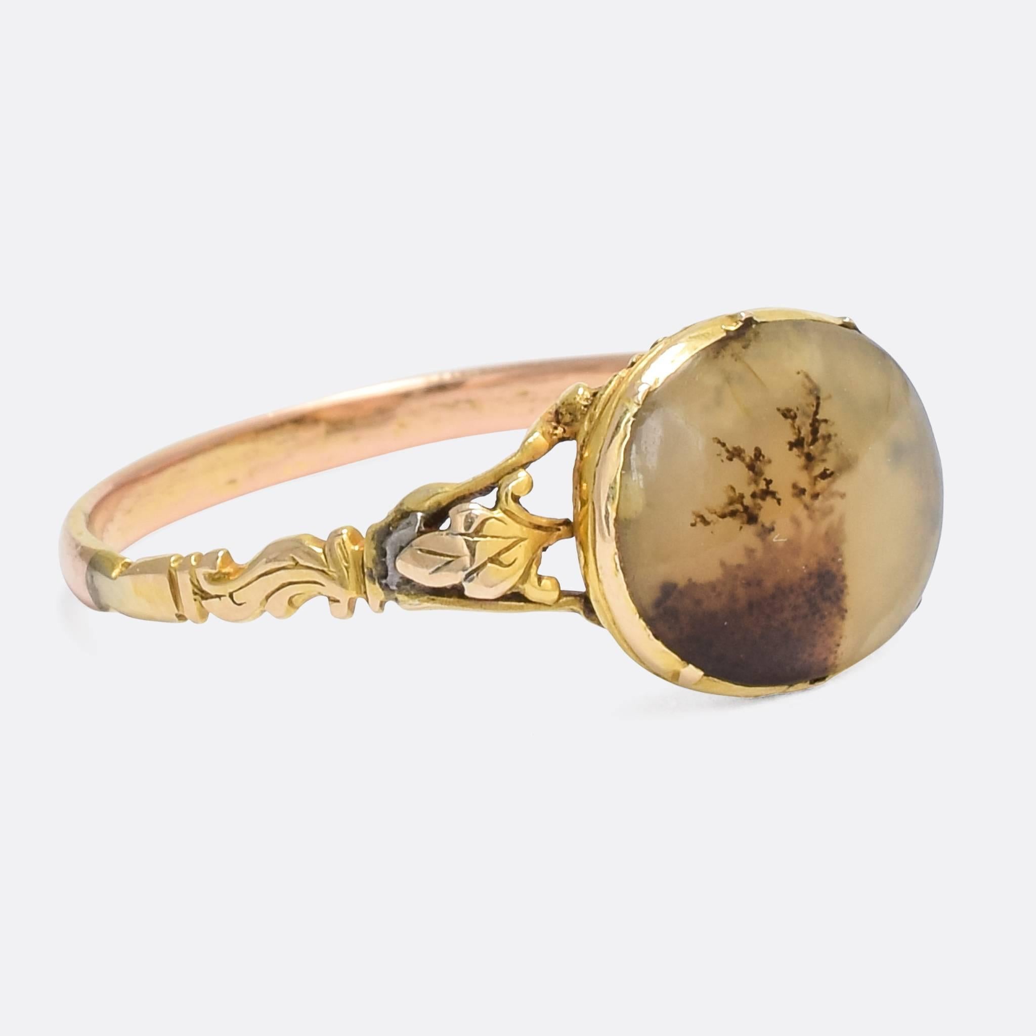 A beautiful antique ring, the head set with a dendritic agate landscape stone in a closed back setting. Very typical of the early 19th Century, the split shoulders have an applied leaf design, and the back of the head is fluted. A fine example of