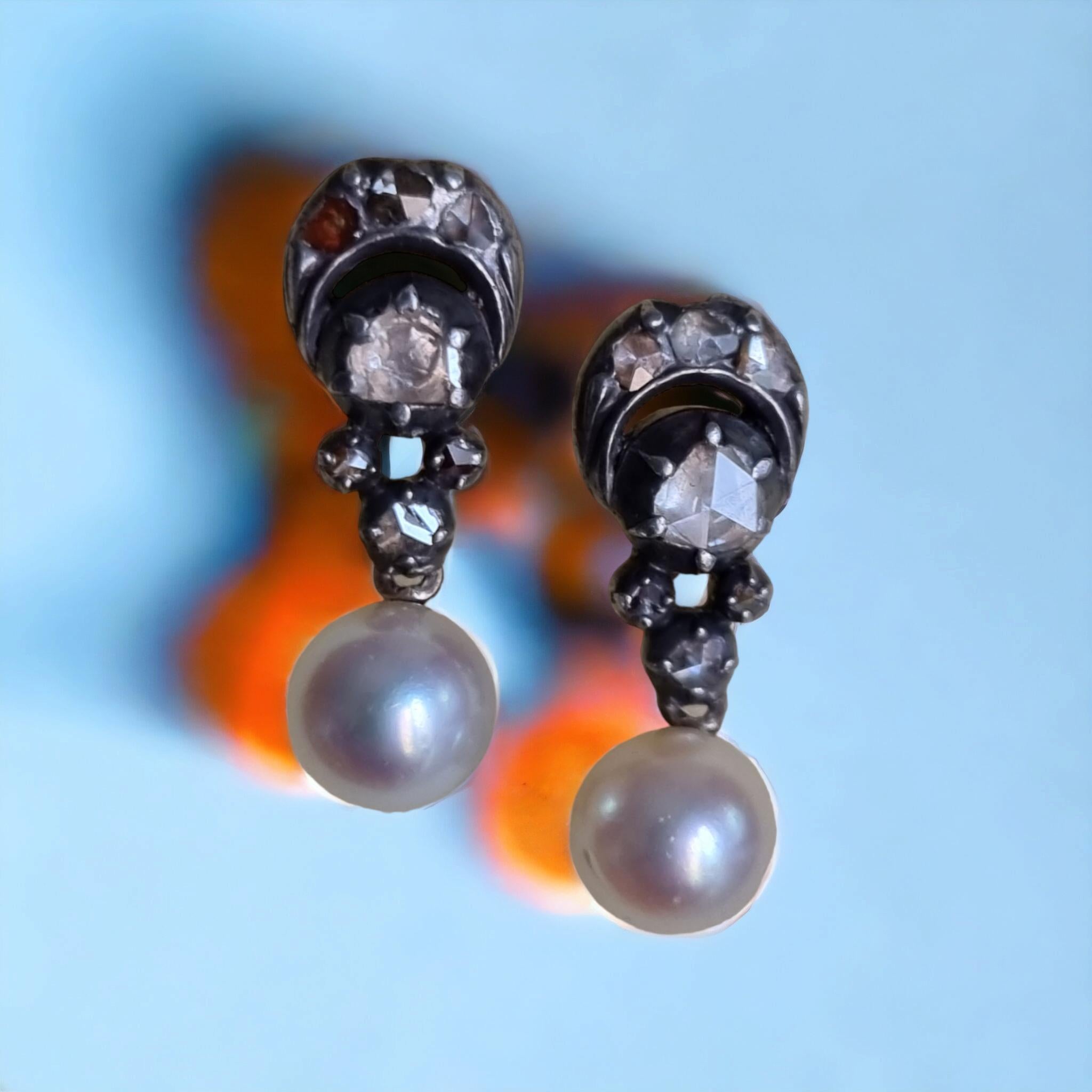 Antique Georgian Diamond and Pearl Dangle Earrings. 

Rare and ravishing Georgian era pair of earrings. Hand fabricated in silver over gold dating back to the early 1800s (19th Century). It consists of 2 central and 12 smaller glittering rose-cut
