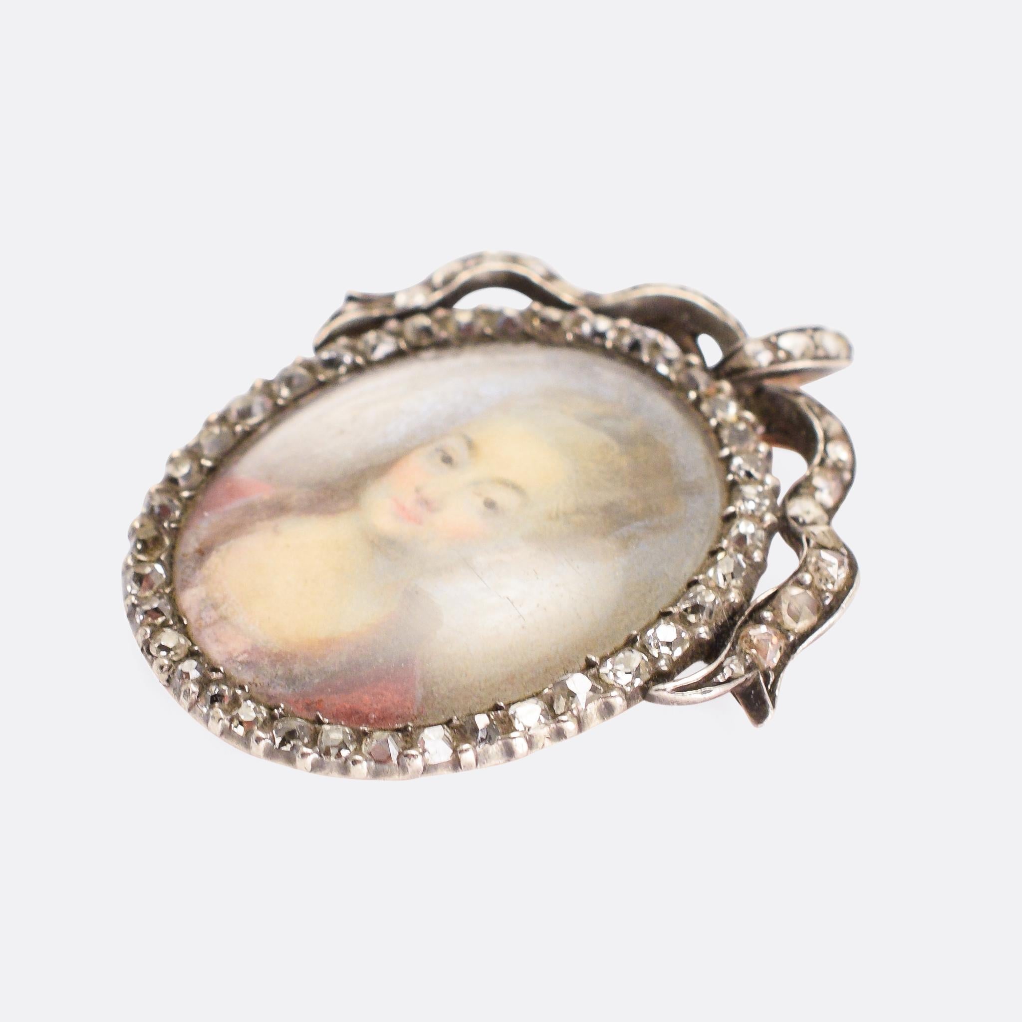 A superb antique portrait miniature pendant depicting a lady wearing pearl earrings and a scarlet dress. The border is set with rose cut diamonds, and finished with an pretty diamond-set bow at the top (which cleverly doubles as the bail). It dates