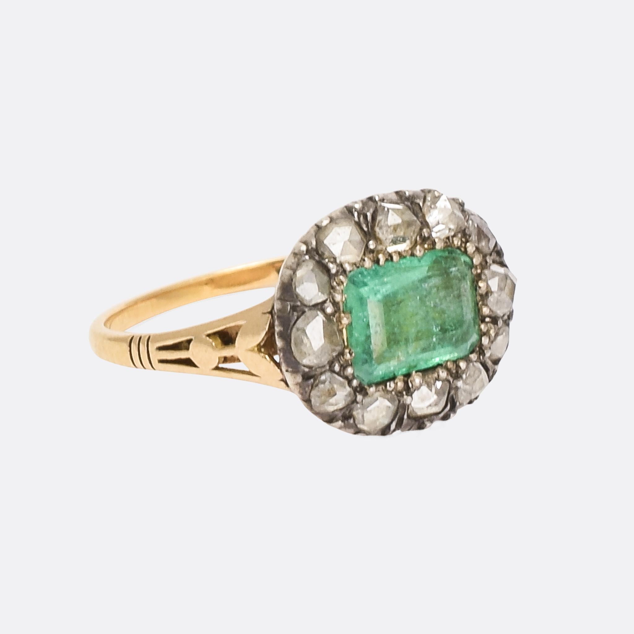 A superb 18th Century cluster ring set with a principal emerald within a halo of rose cut diamonds. It was made in England – circa 1790 – under the reign of George III. Crafted in 15 karat gold with silver settings, the ring features fluted