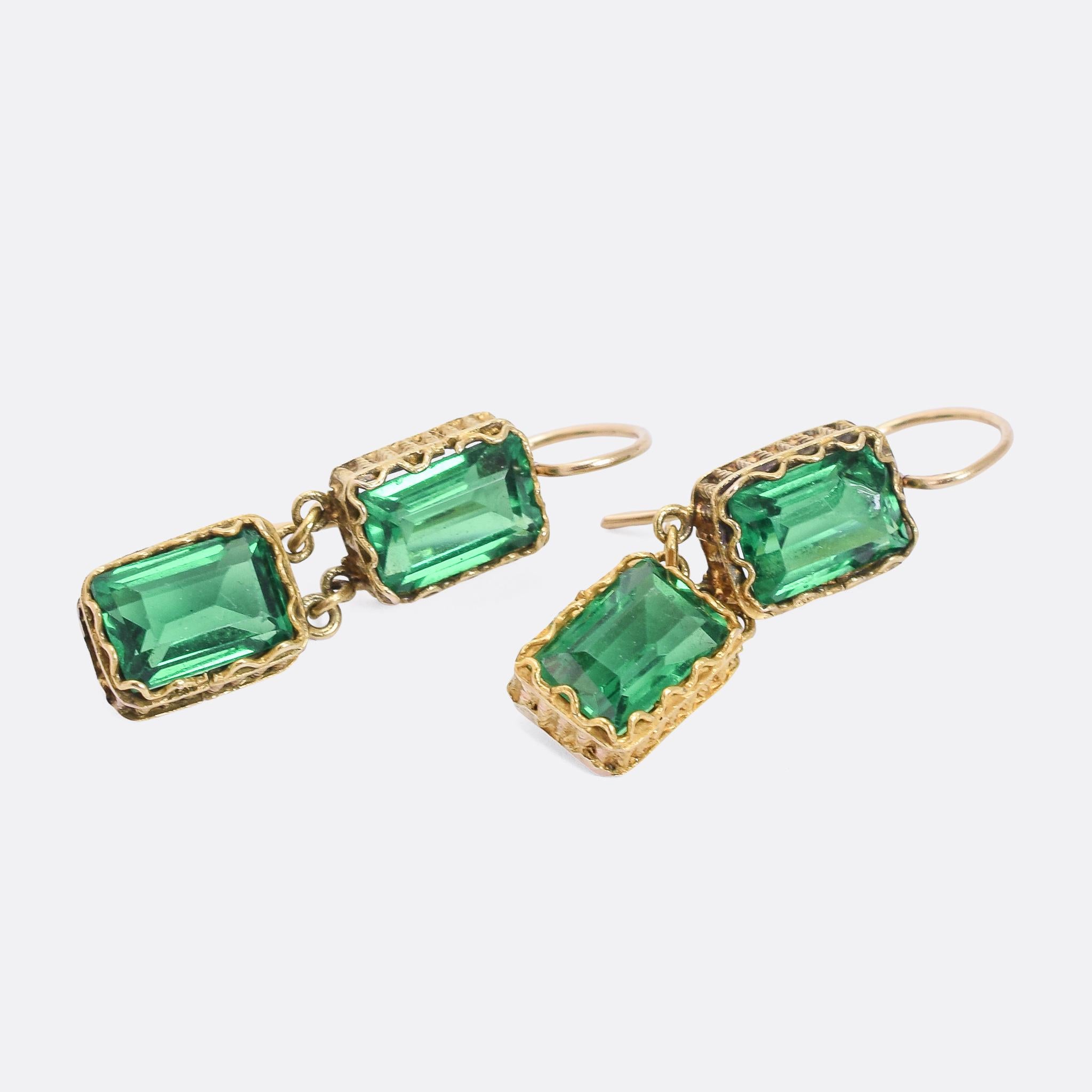 A fine pair of antique earrings dating from the Georgian period, circa 1820. Each one is set with two vibrant green paste gemstones, individually set in articulated 15 karat gold mounts that feature textured sides. It's a gorgeous colour