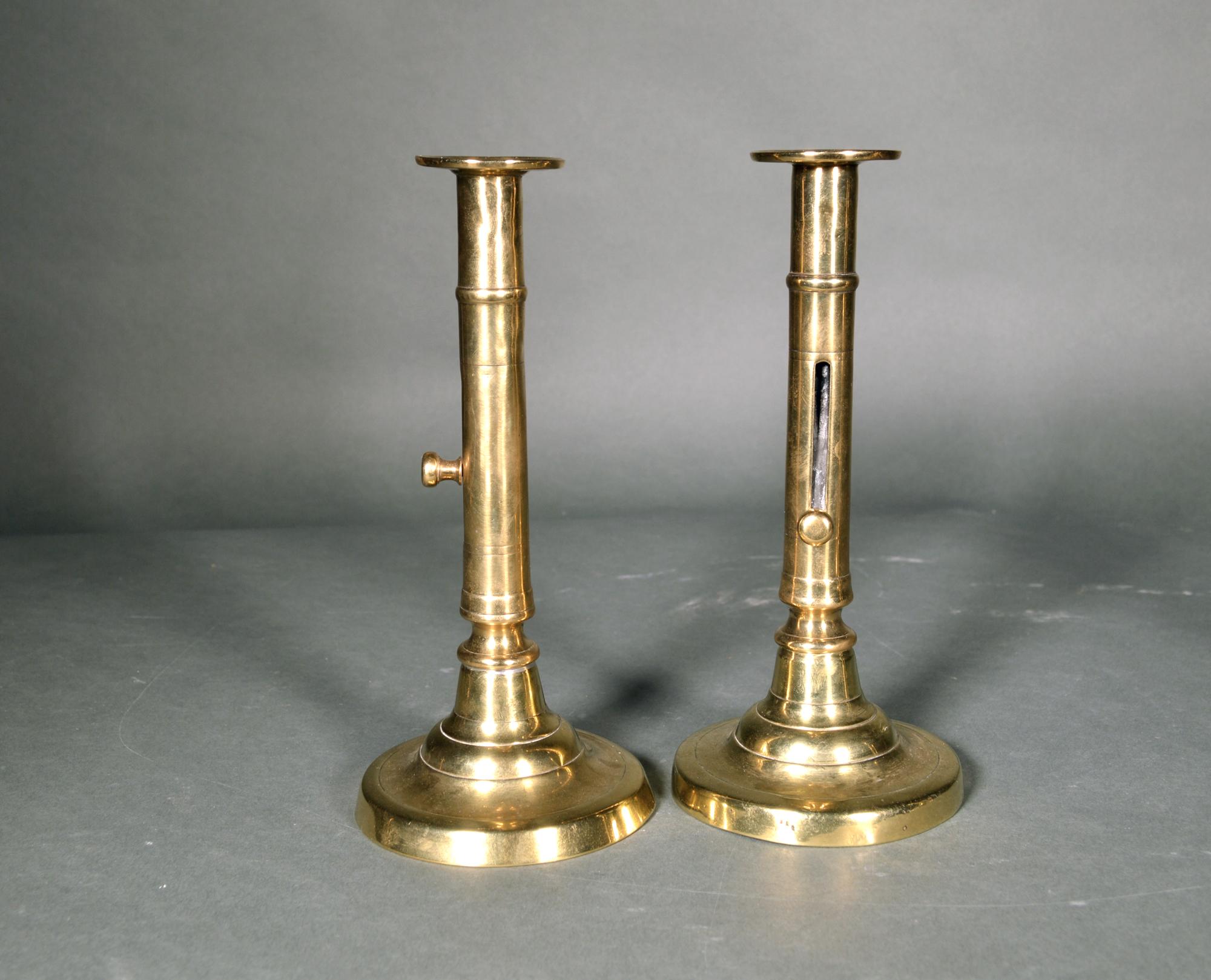 Antique Georgian English brass side-eject candlesticks- pair,
circa 1770-1800.

The pair of brass push-up brass candlesticks have a circular domed base with a central column with a button end mechanism to eject a candle.

Dimensions: 8 1/2