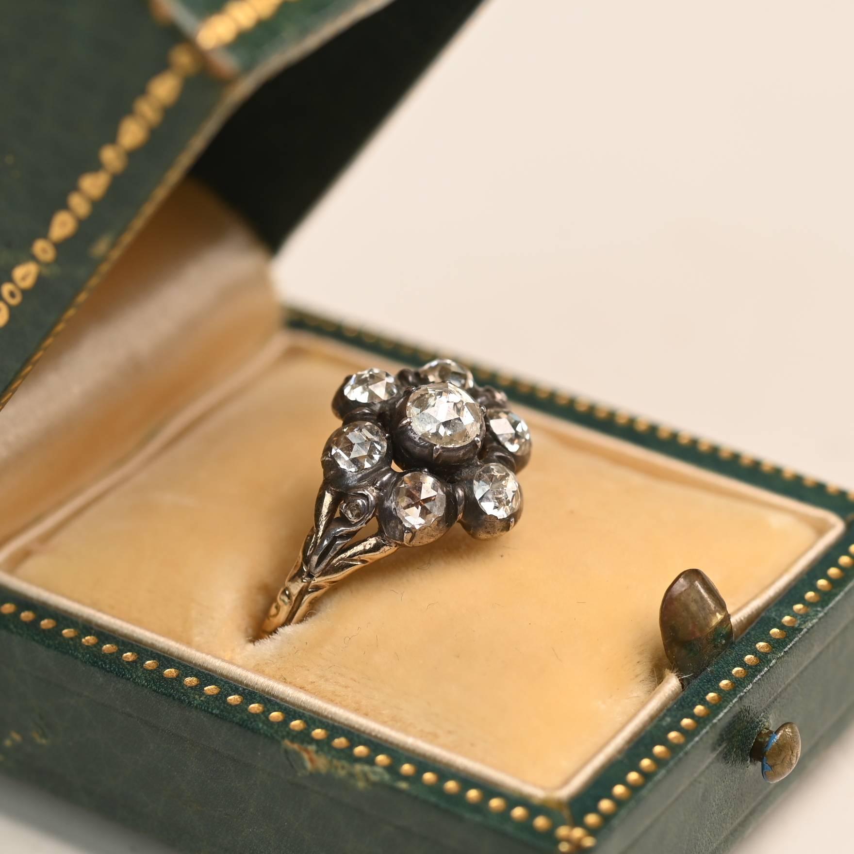 Un affascinante anello a grappolo di diamanti di epoca georgiana, realizzato a mano nel 1800 circa, con circa 0,7 carati di diamanti in totale. I diamanti hanno un colore complessivo J-K e una purezza VS2-SI1, disposti in un delicato grappolo che