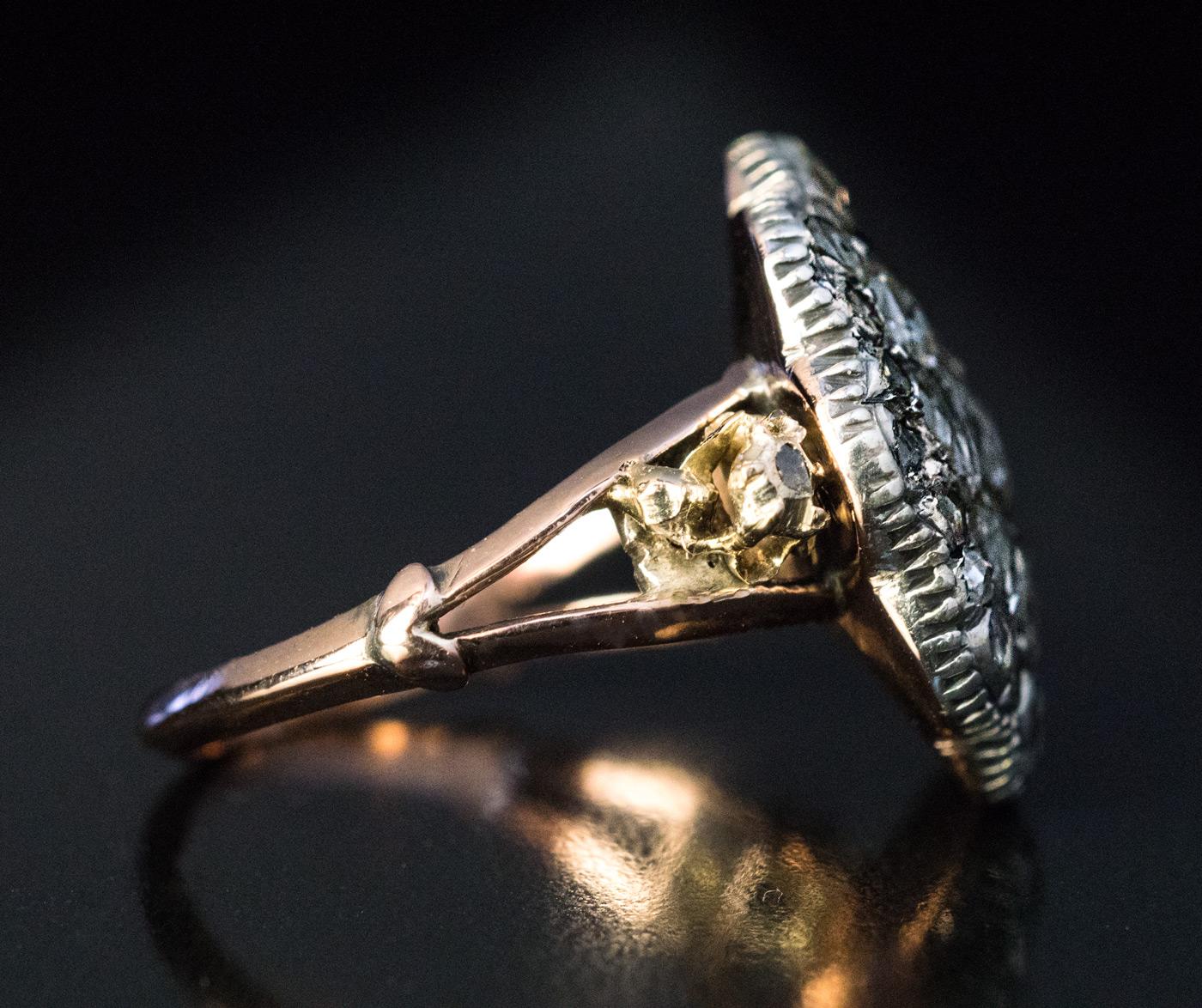 A late 18th century silver-topped gold cluster ring is centered with a 5.6 mm old rose cut diamond encircled by two rows of rose cut diamonds of various shapes and sizes. The diamonds are set in a closed back setting.

Diameter of the diamond