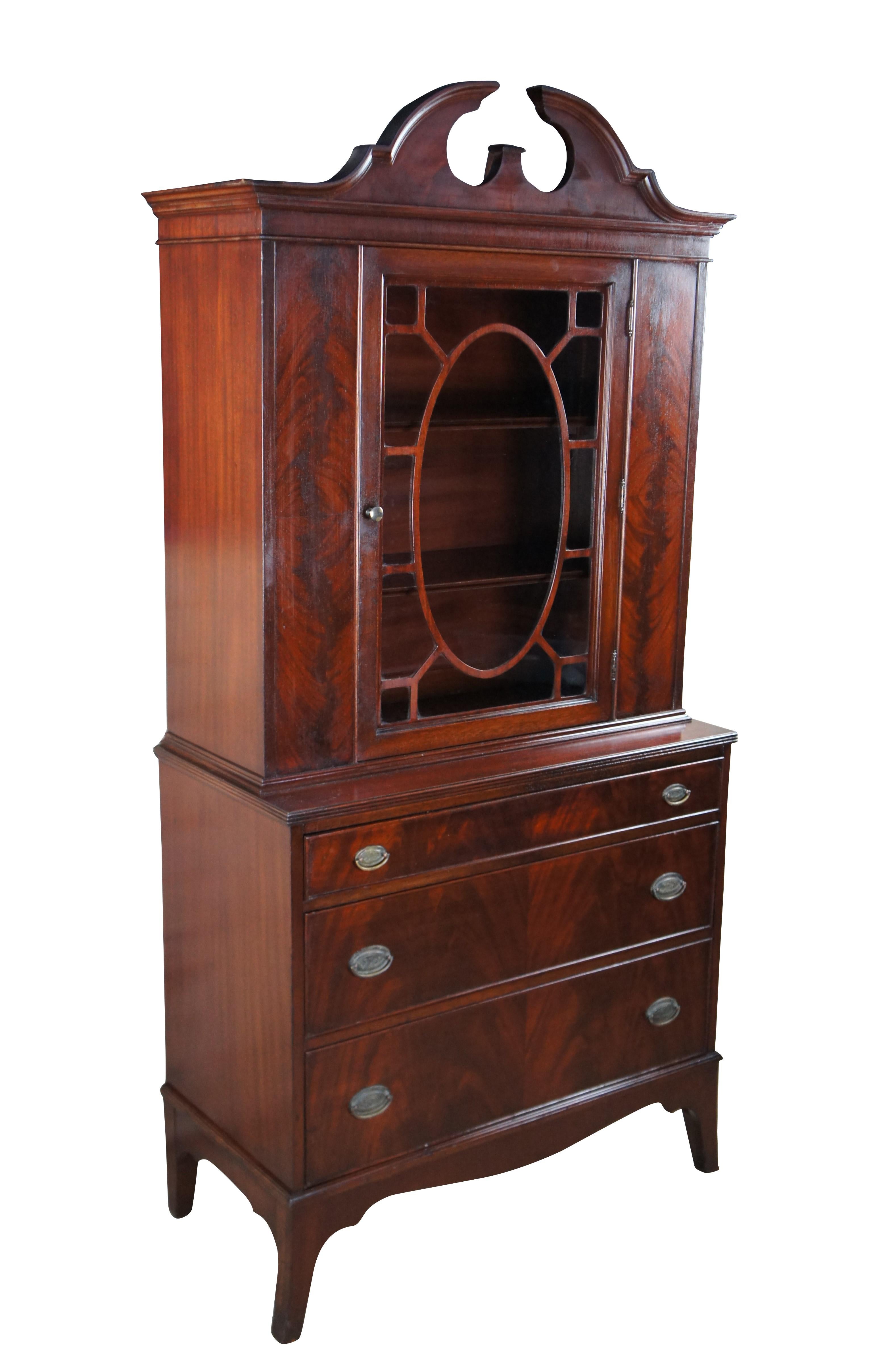 Antique Georgian style cupboard / china cabinet / hutch.  Made of flamed mahogany featuring open pediment crown over large fretwork door that opens to multiple shelves with plate grooves over a three drawer chest and serpentine base with flared