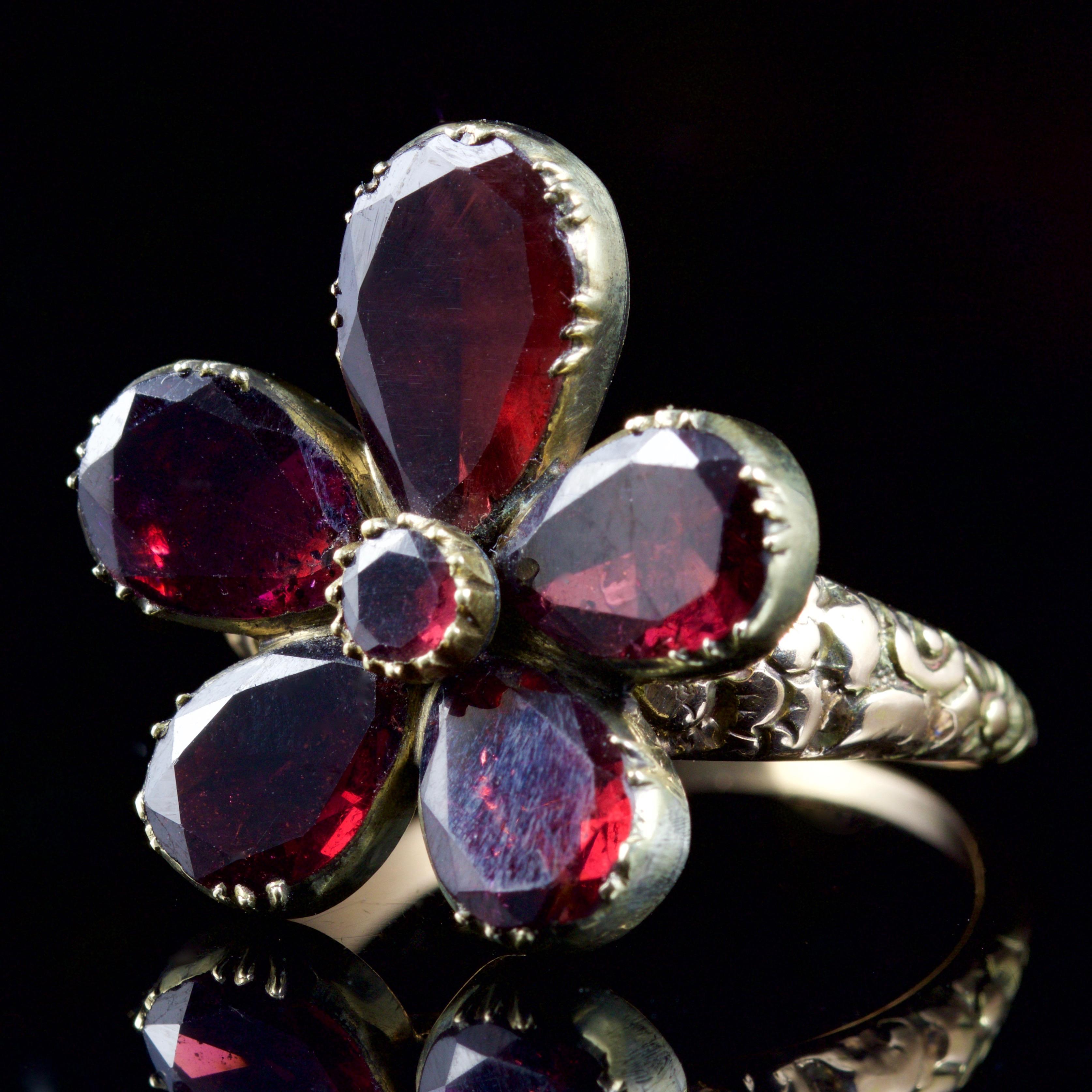 This very beautiful flat cut Garnet flower ring is, Circa 1800.

The ring boasts beautiful Garnets in the shape of a flower, set in an 18ct Yellow Gold gallery.

Originally this looks to be part of a Georgian lavaliere and has been converted to a