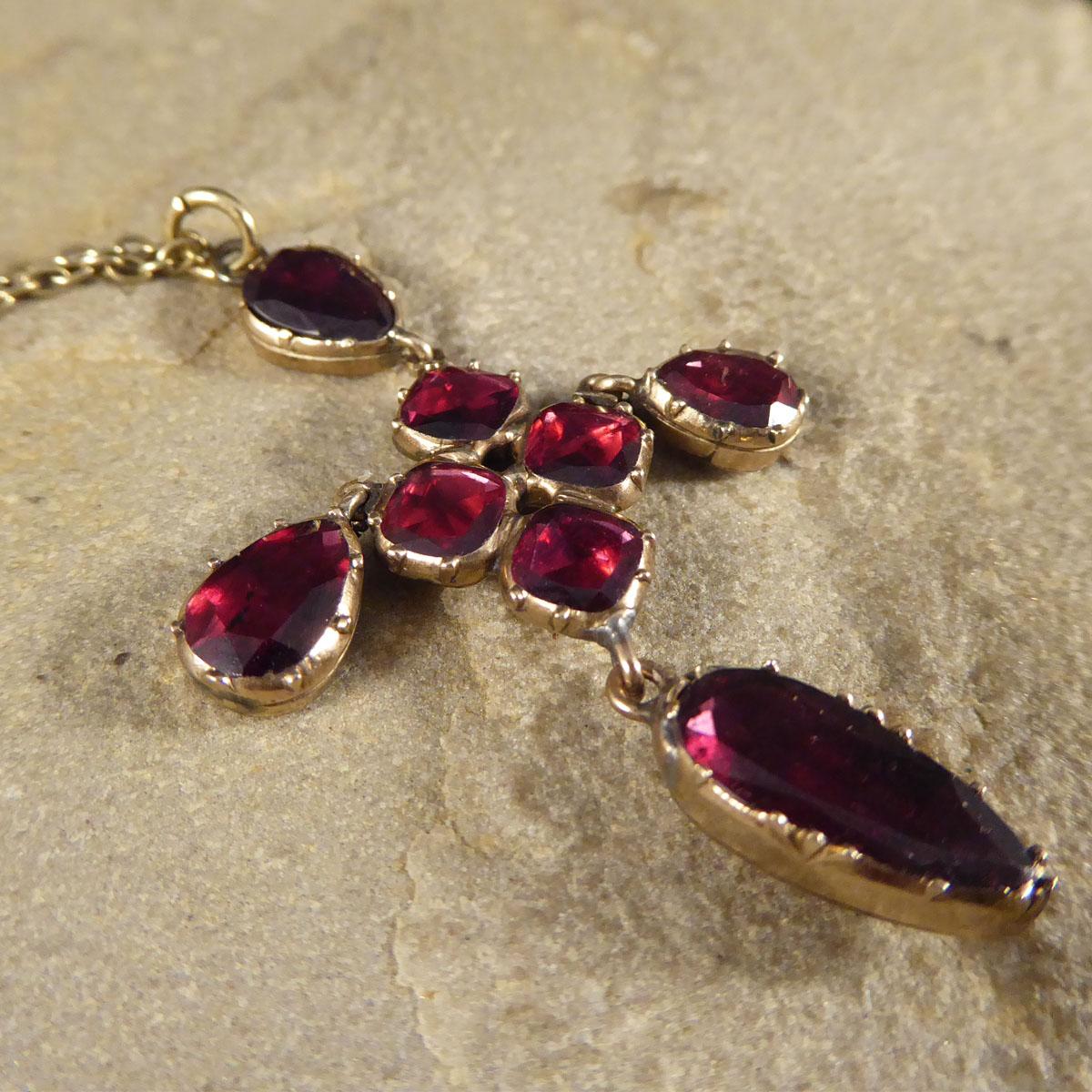 A gorgeous necklace showing such quality aesthetic from the Georgian era. It is in a crucifix shape and and set with Garnets that have foiled behind, a popular Georgian style. The crucifix shape is made from a centre for four garnets with a drop