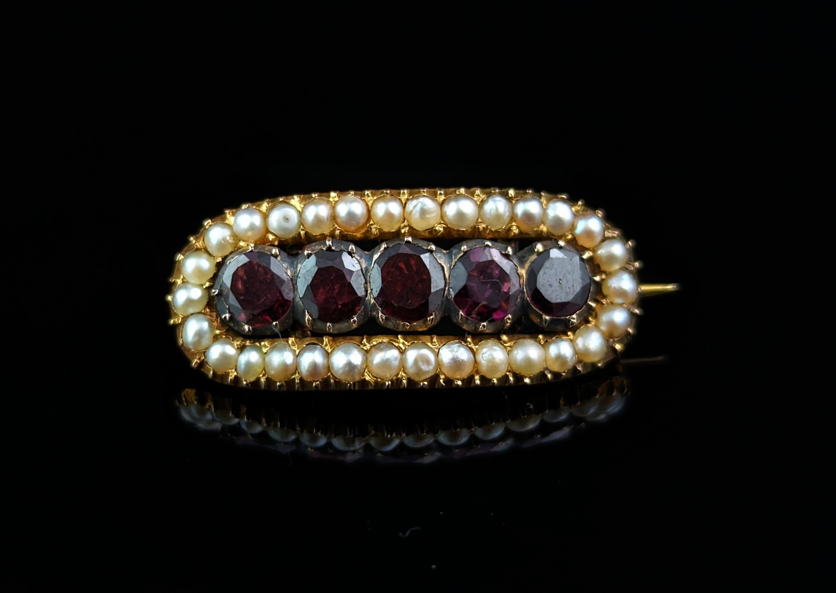 A very beautiful antique Georgian Garnet and Pearl brooch.

This is an elongated oval shaped brooch, perfect for securing a fichu or lace ruffle at the neck.

It is crafted in rich 18ct yellow gold and set with a row of deep rich red, flat cut
