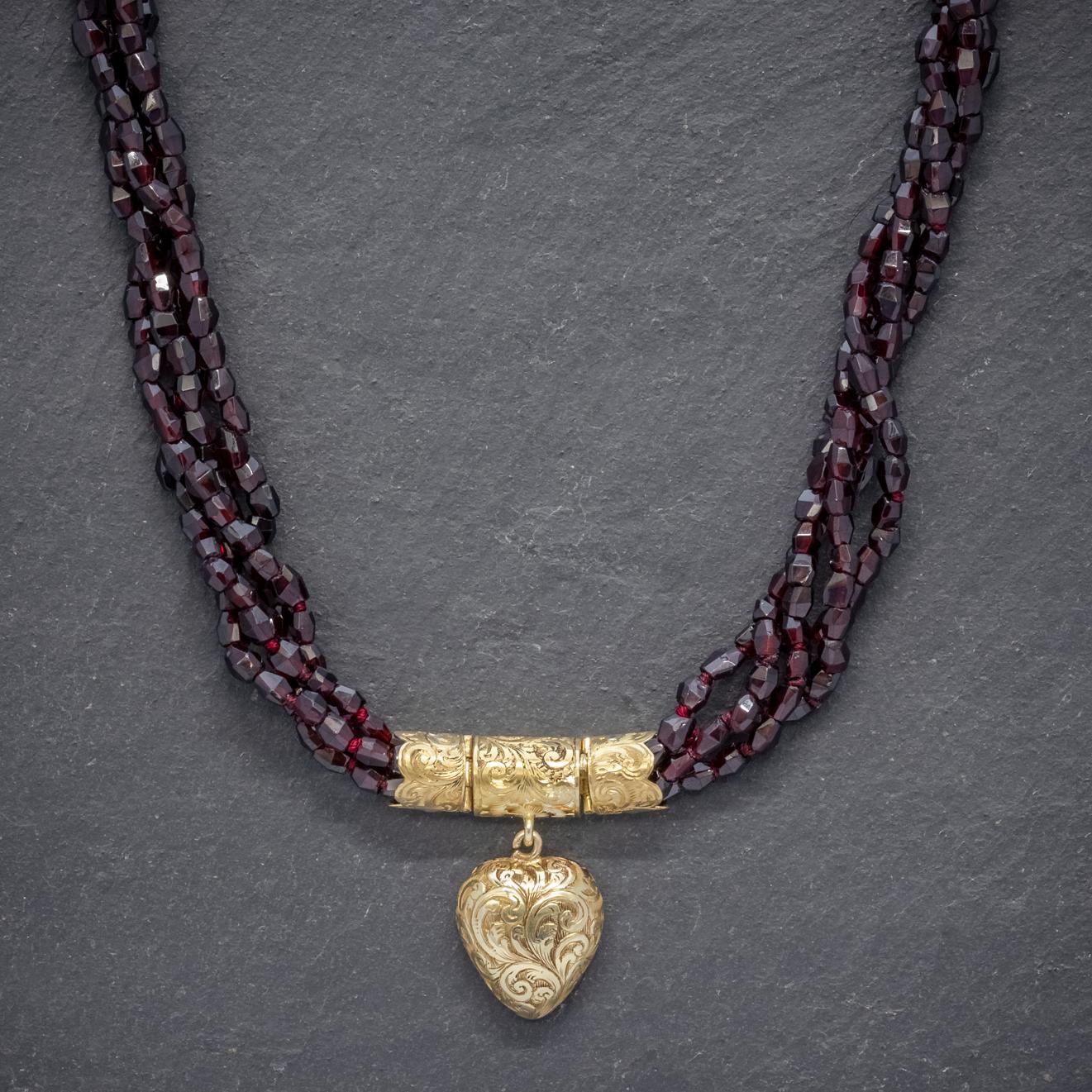 A spectacular antique Georgian necklace made up of four strands lined with faceted Garnet beads forming a twisting bundle that shimmers and sparkles with a deep red wine-coloured hue.  

The crowning feature of the necklace is a beautiful 18ct