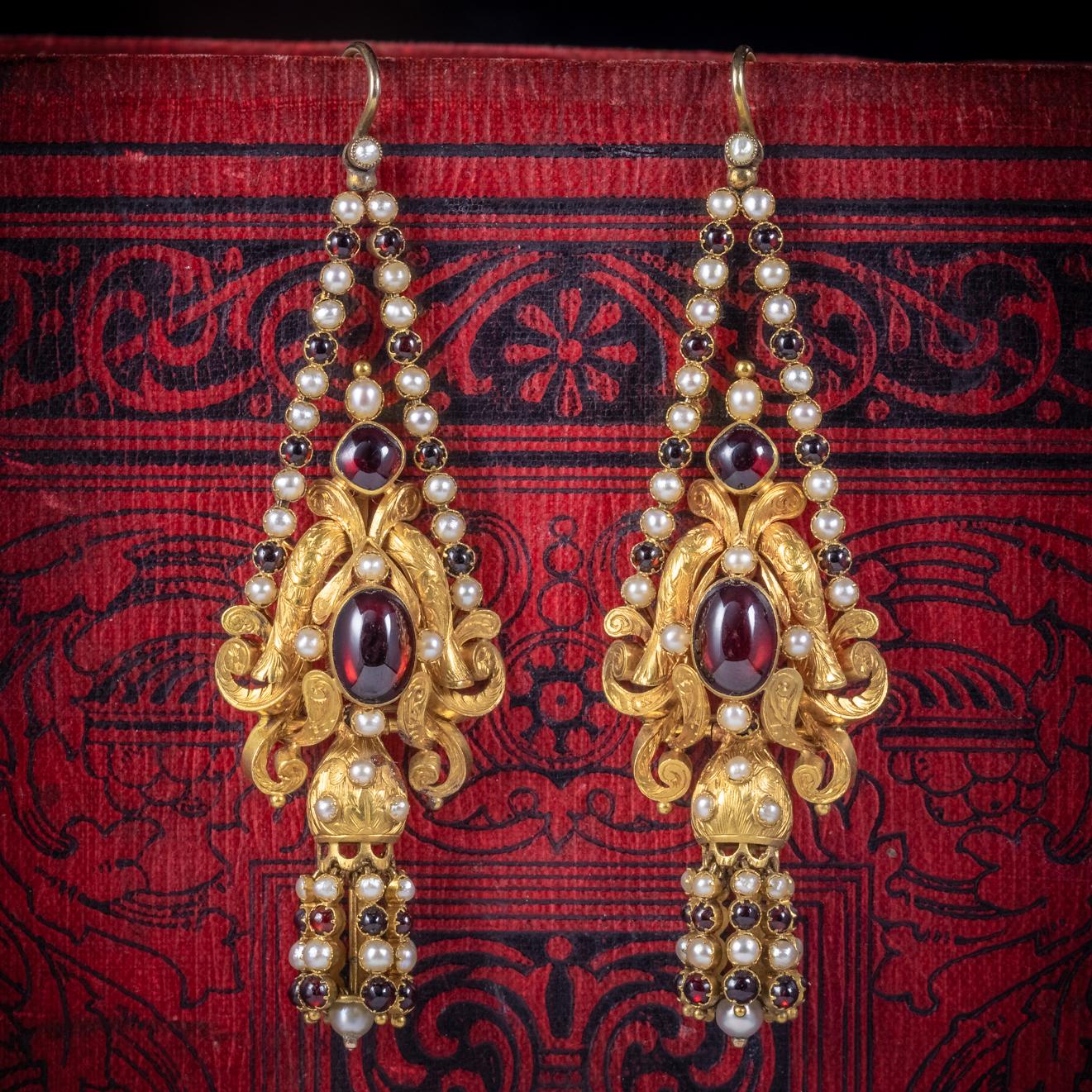 A spectacular pair of antique Georgian drop earrings C. 1800 adorned with deep red Garnet’s and lovely natural Pearls. 

Each earring is lined with Garnet’s and Pearls leading to a fabulous engraved gallery crowned with a larger Cabochon Garnet and