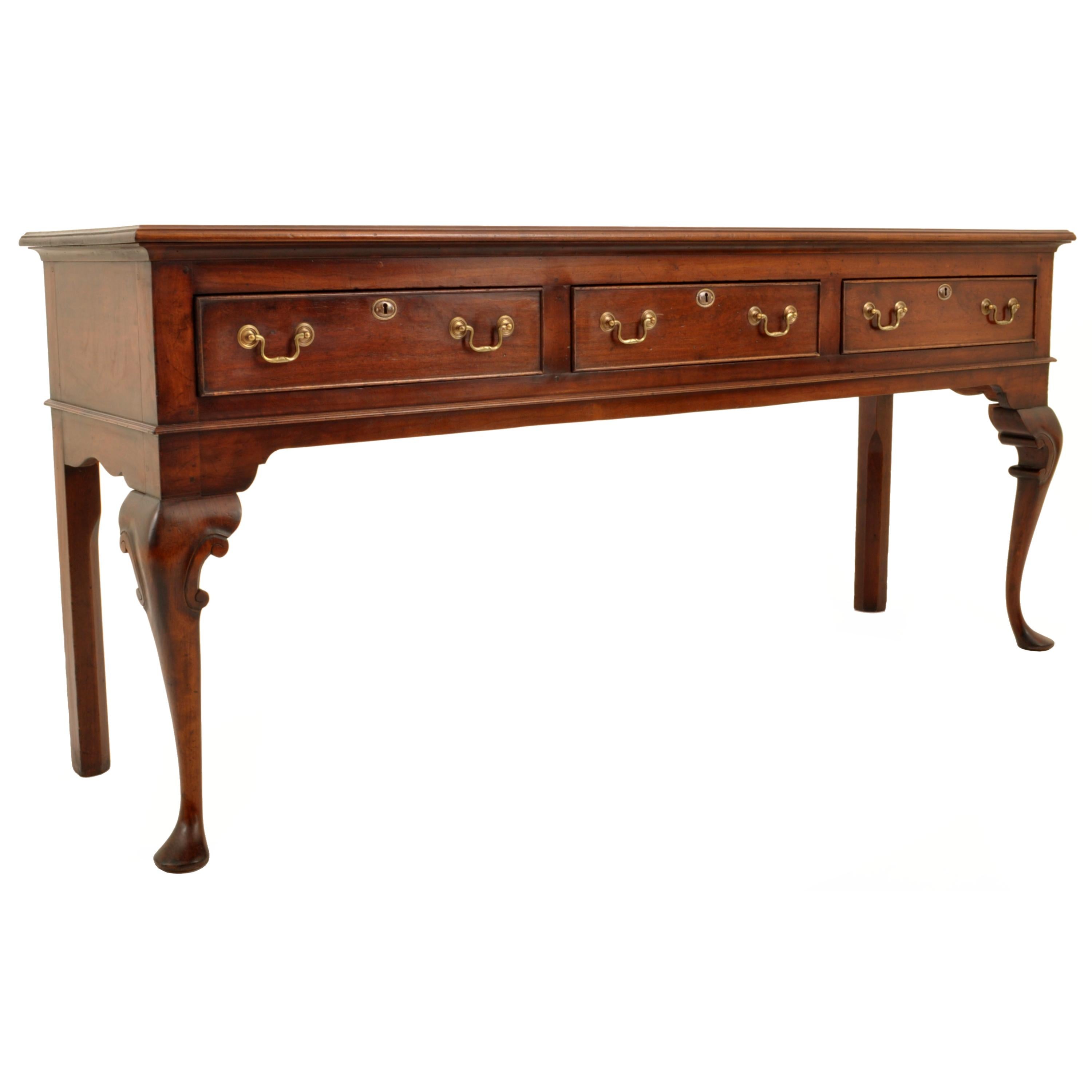 A good quality antique walnut Georgian long Welsh dresser base server, circa 1760.
The dresser having a slightly overhanging top above three cockbeaded drawers each with the original brass handles and escutcheons, the dresser raised on cabriole