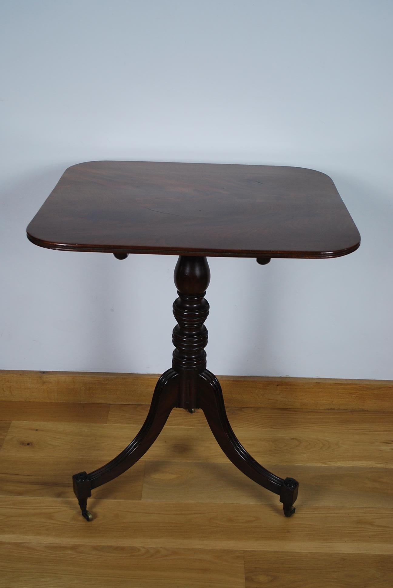This is a very fine quality Georgian antique mahogany tripod table with rectangular top. It has out swept legs and turned feet standing on brass castors.