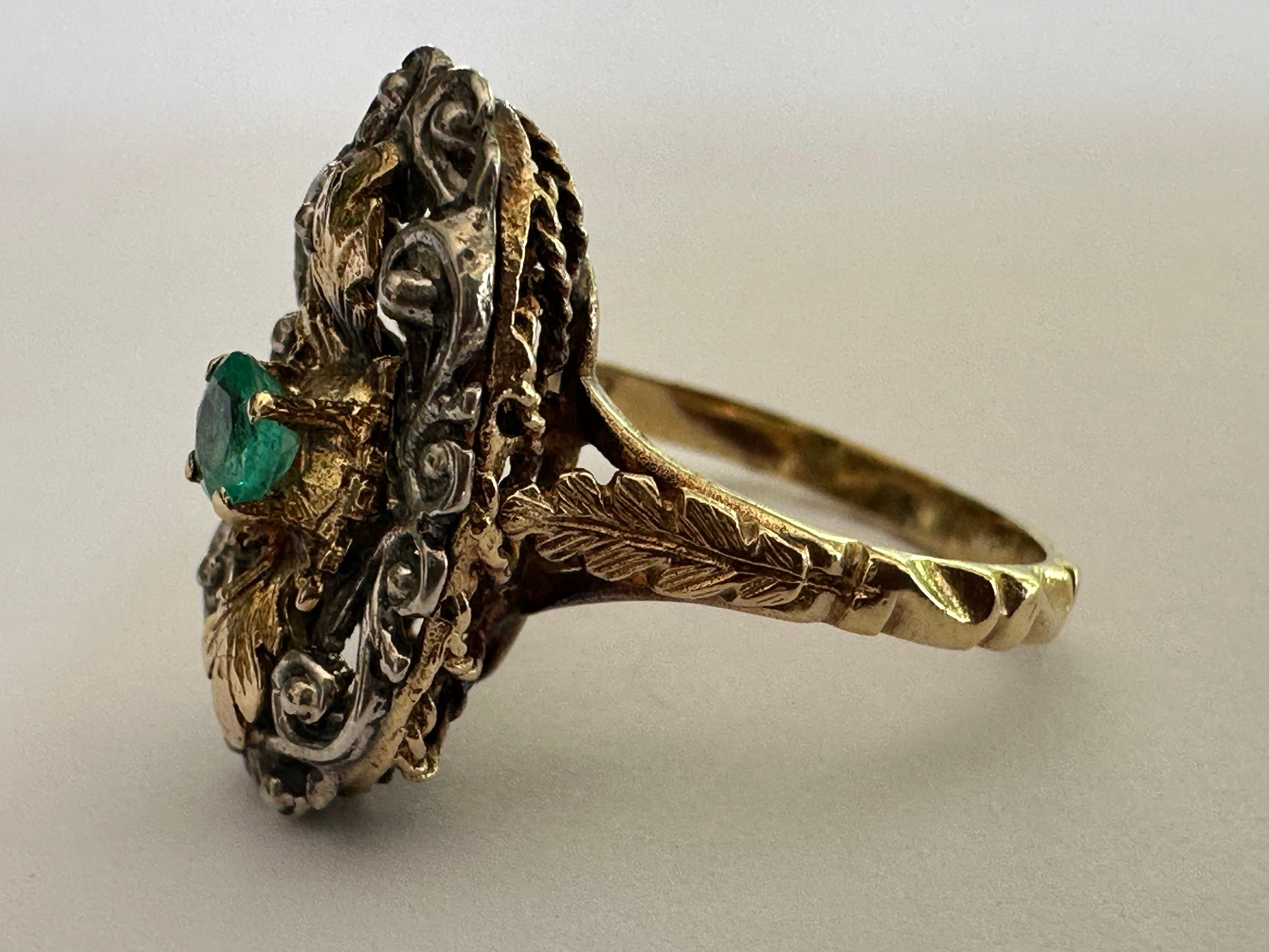 A 3.5mm round green emerald centers this rare antique two-tone ring set in 18K yellow gold and silver and accented with intricate hand-engraved details. Circa mid-19th century. 

