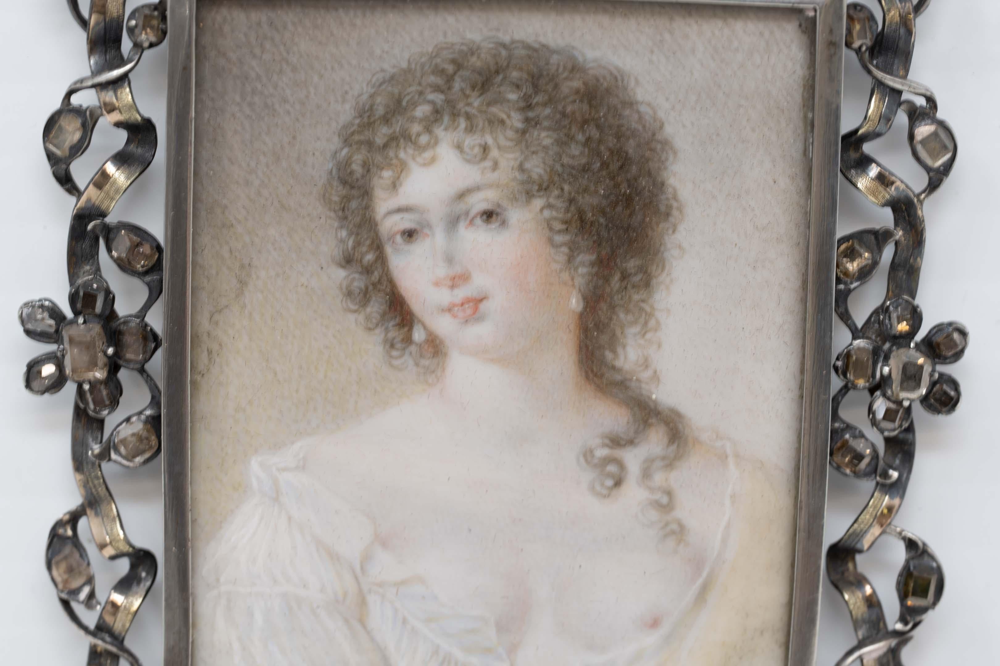 Portrait miniature d'une jeune femme, peint à la main au 18e siècle, dans un cadre en argent massif, entouré de cristaux carrés, rectangulaires et taillés à l'ancienne (l'un d'entre eux est manquant ou cassé). La miniature n'est pas signée. Les