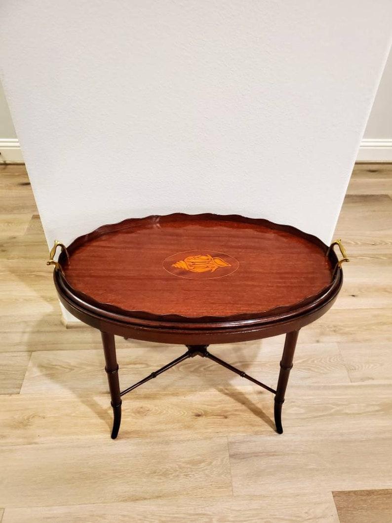 An elegant turn of the late 18th / early 19th century finely made Georgian mahogany low table. Circa 1800; England 

Wonderful oval shaped butler server tray, handcrafted from solid and inlaid mahogany, with raised pie crust edge scalloped