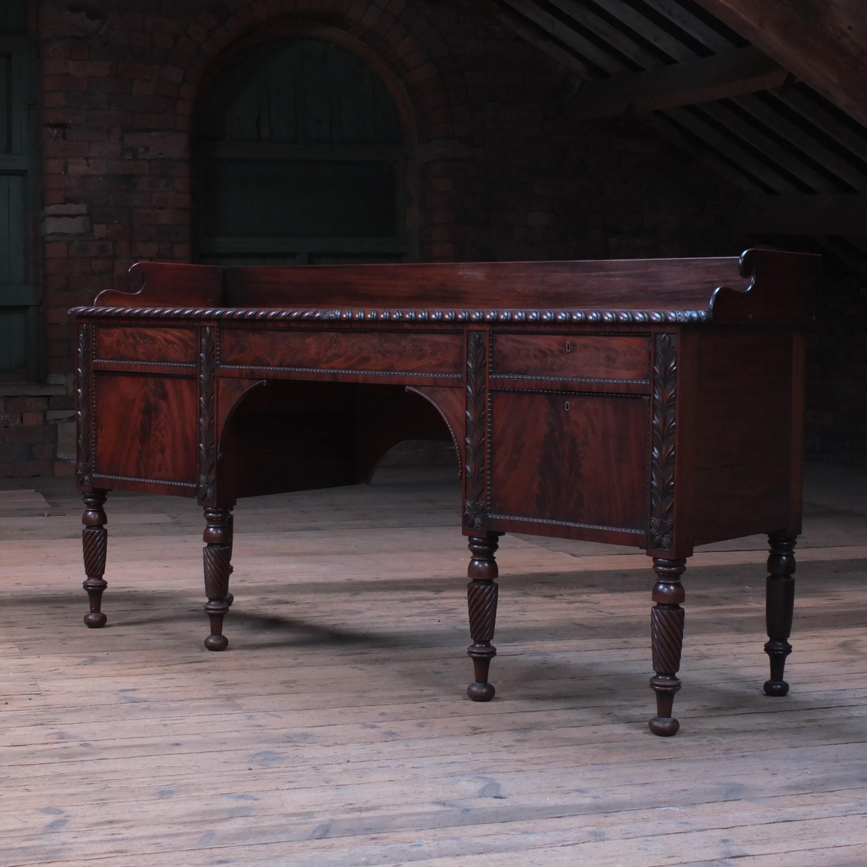 A large scale early 19th century mahogany sideboard. Raised on turned reeded legs with bun feet. Nicely figured flame mahogany veneer to the drawer fronts and a gadrooned top edge. In unpolished country house condition which is solid and very much