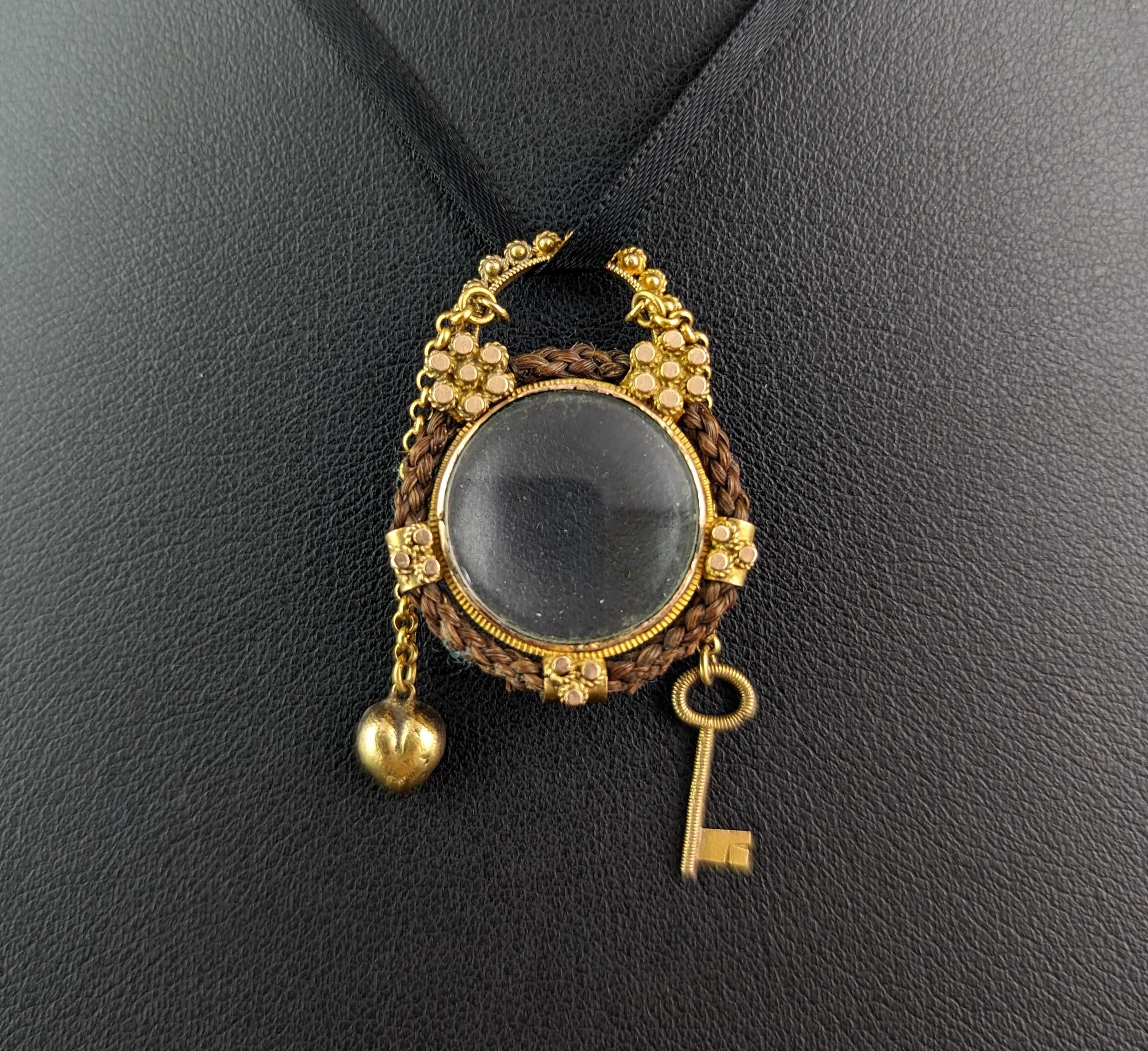 A truly magical piece of antique Georgian mourning jewellery.

This early 19th century locket is designed as a padlock, circular in shape with a hairwork border and beautiful tiny cannetille and floral detailing in rich 18ct yellow gold.

Such