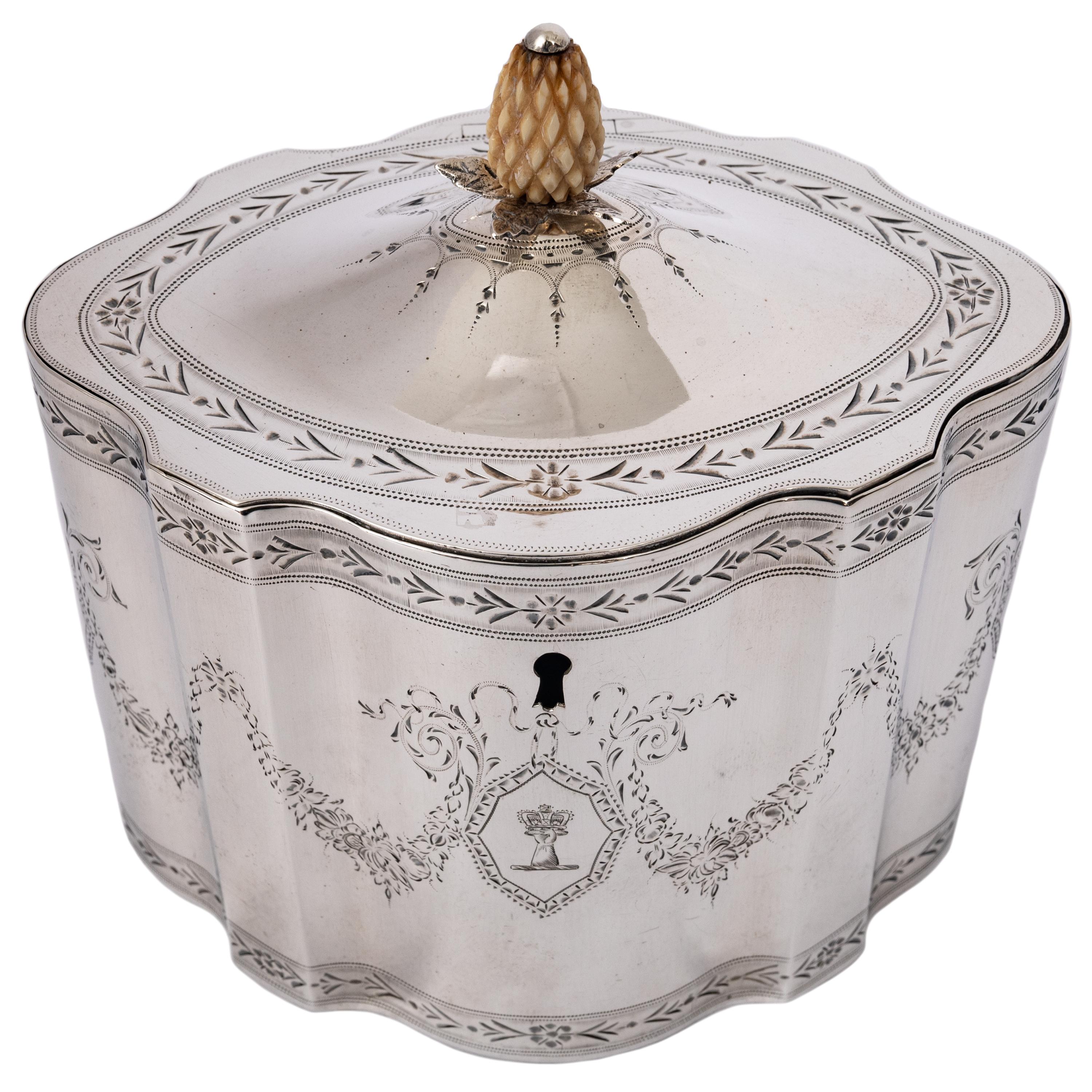 A fine antique Georgian engraved sterling silver tea caddy, by Henry Chawner, London, 1787.
Of fluted oval form with bright-cut floral borders with flower heads and having a hinged locking lid with a carved ivory pineapple finial with a silver