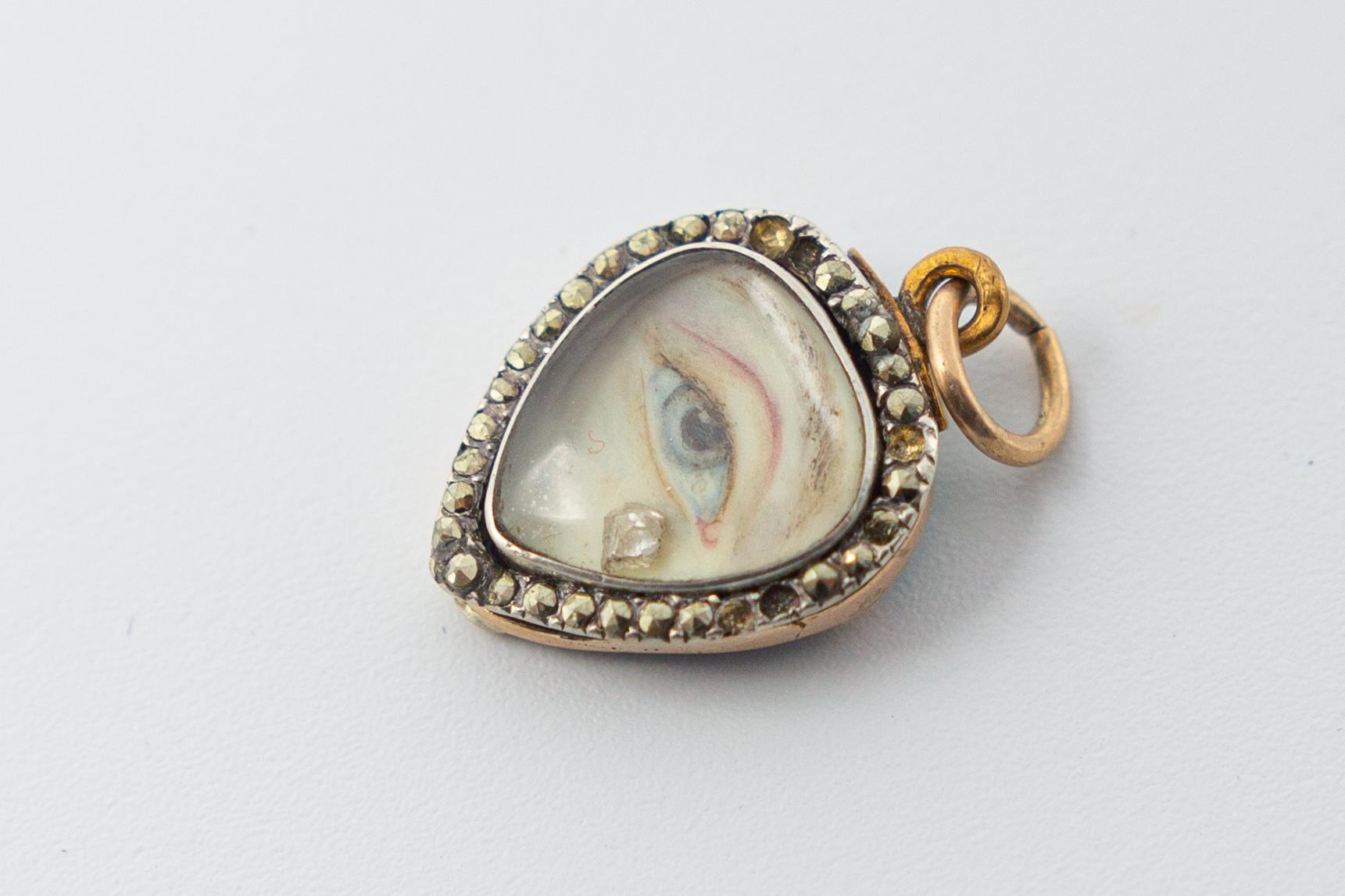 Antique Georgian lovers eye with a diamond tear drop mourning heart pendant. This lovers eye finely painted and appears to be on wafer. The pendant is 9k gold and silver with a blue enamel back, the border is set with cut steels which sparkle really