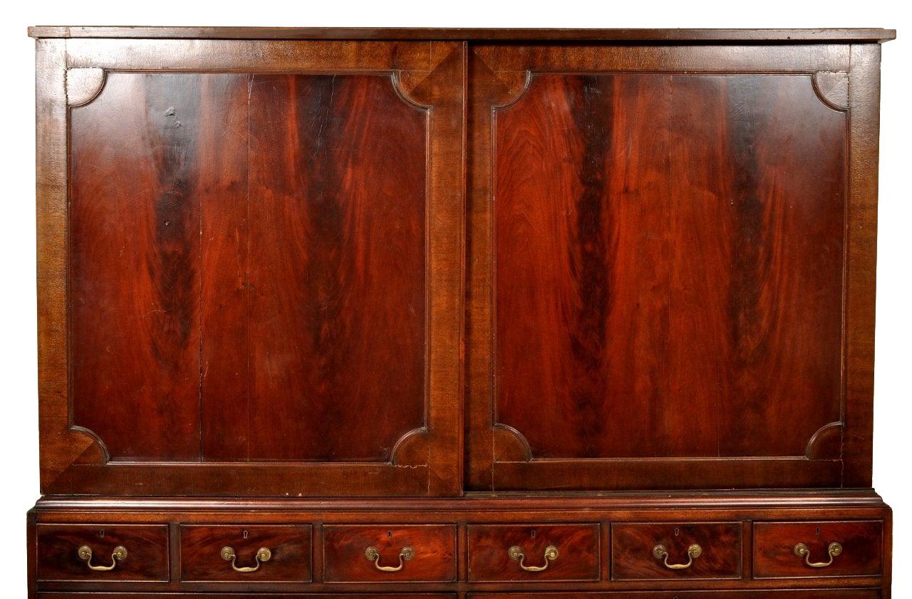 Antique Georgian mahogany linen press, circa 1800. The linen press in two sections, the top section unusually having a pair of twin sliding doors enclosing sliding linen trays. The base having twin banks of drawers configured with three short over