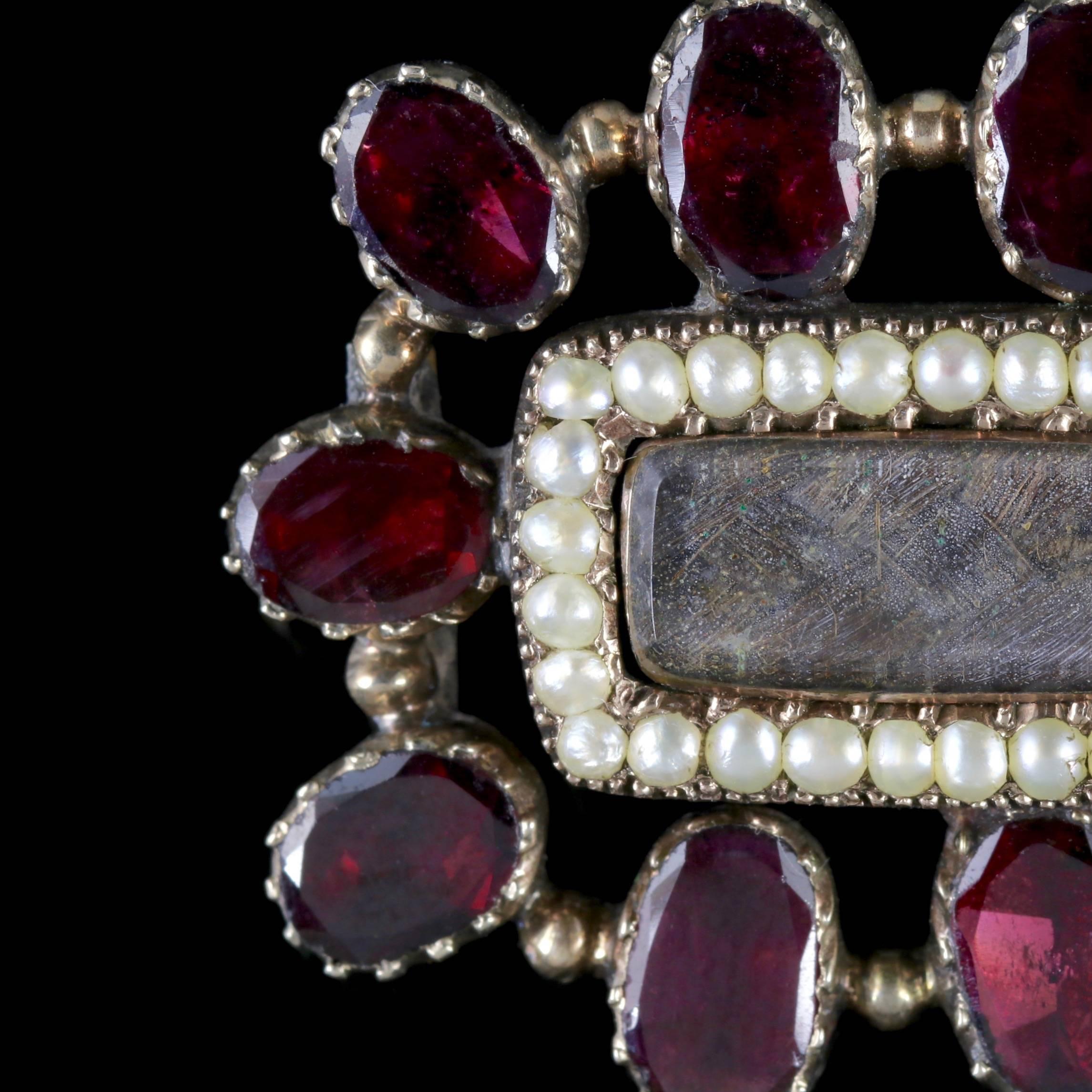 This wonderful antique Garnet and Pearl Mourning brooch is a genuine Georgian piece, Circa 1800.  

The brooch is decorated in ten fabulous flat cut Garnets with a halo of Pearls surrounding the central display window containing lovely plaited hair.