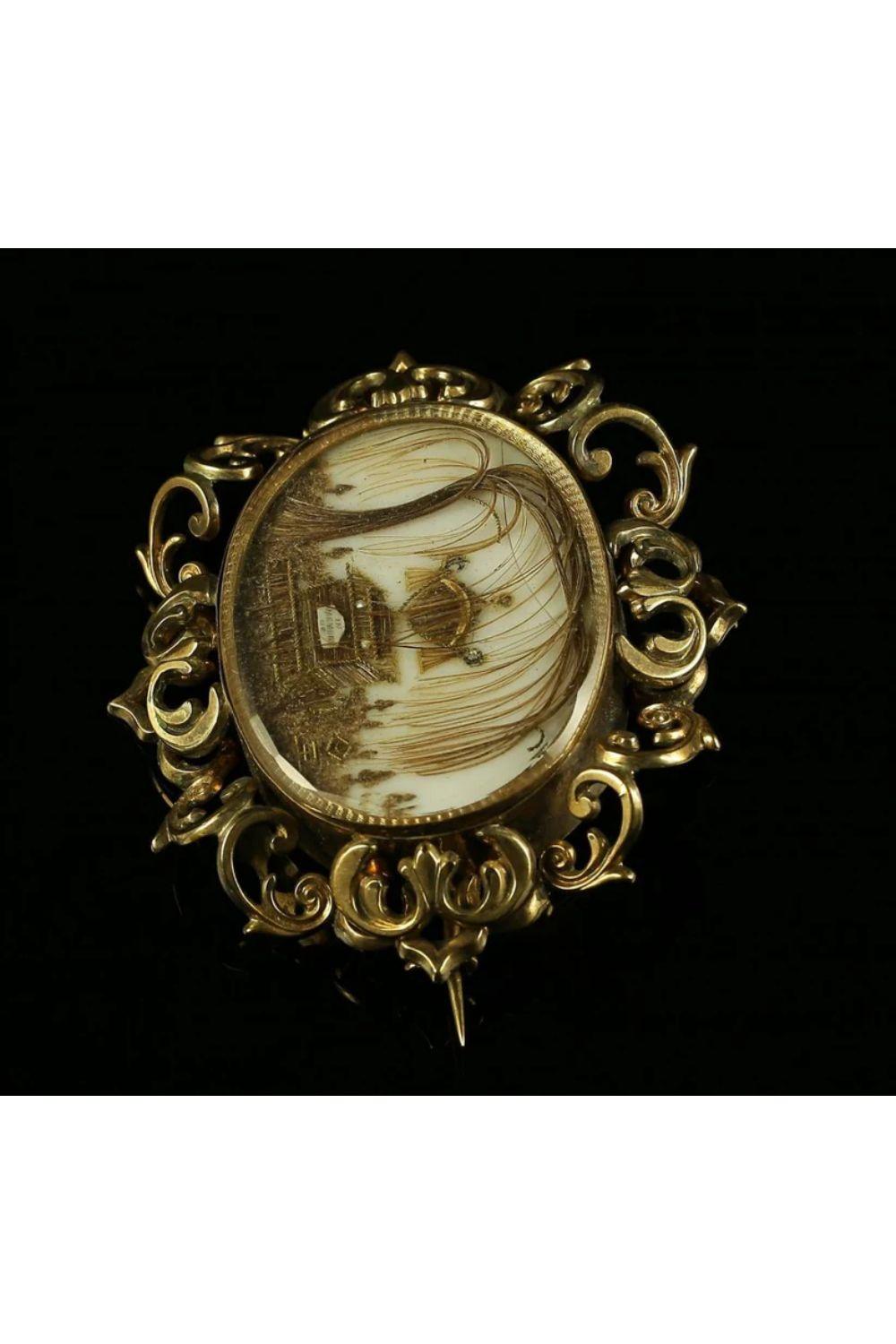 A beautifully preserved antique Georgian Mourning brooch from the late 18th Century featuring a detailed image of an urn and coffin in the centre with the words: “In memory of” written at the front. The image is laid on a mother of pearl base and