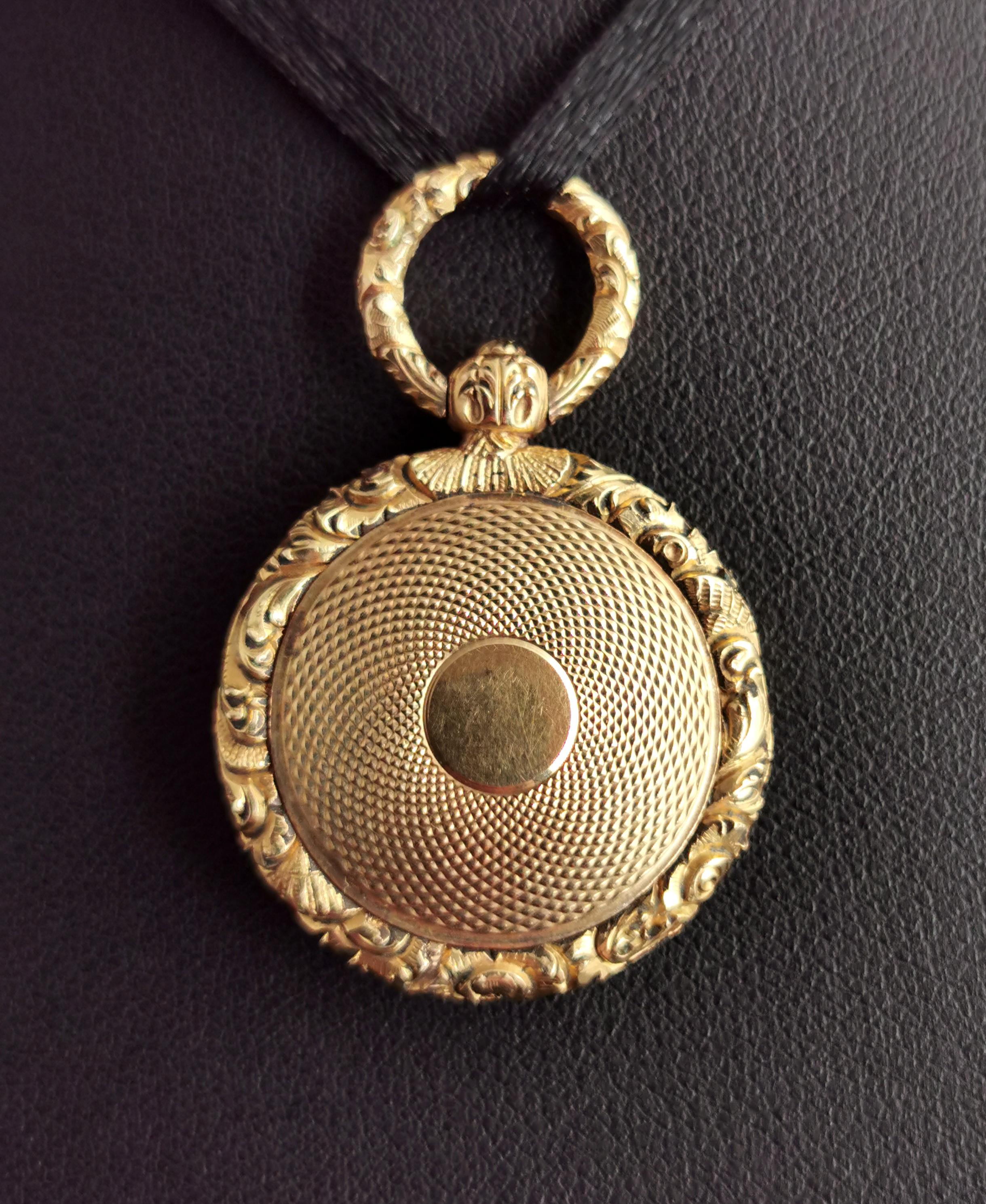 A gorgeous antique, late Georgian era mourning locket.

It is a circular shaped locket with a similar style to a pocket watch, heavily chased and engraved.

The locket has a decorative bow and a push clasp mechanism to open the locket door, within