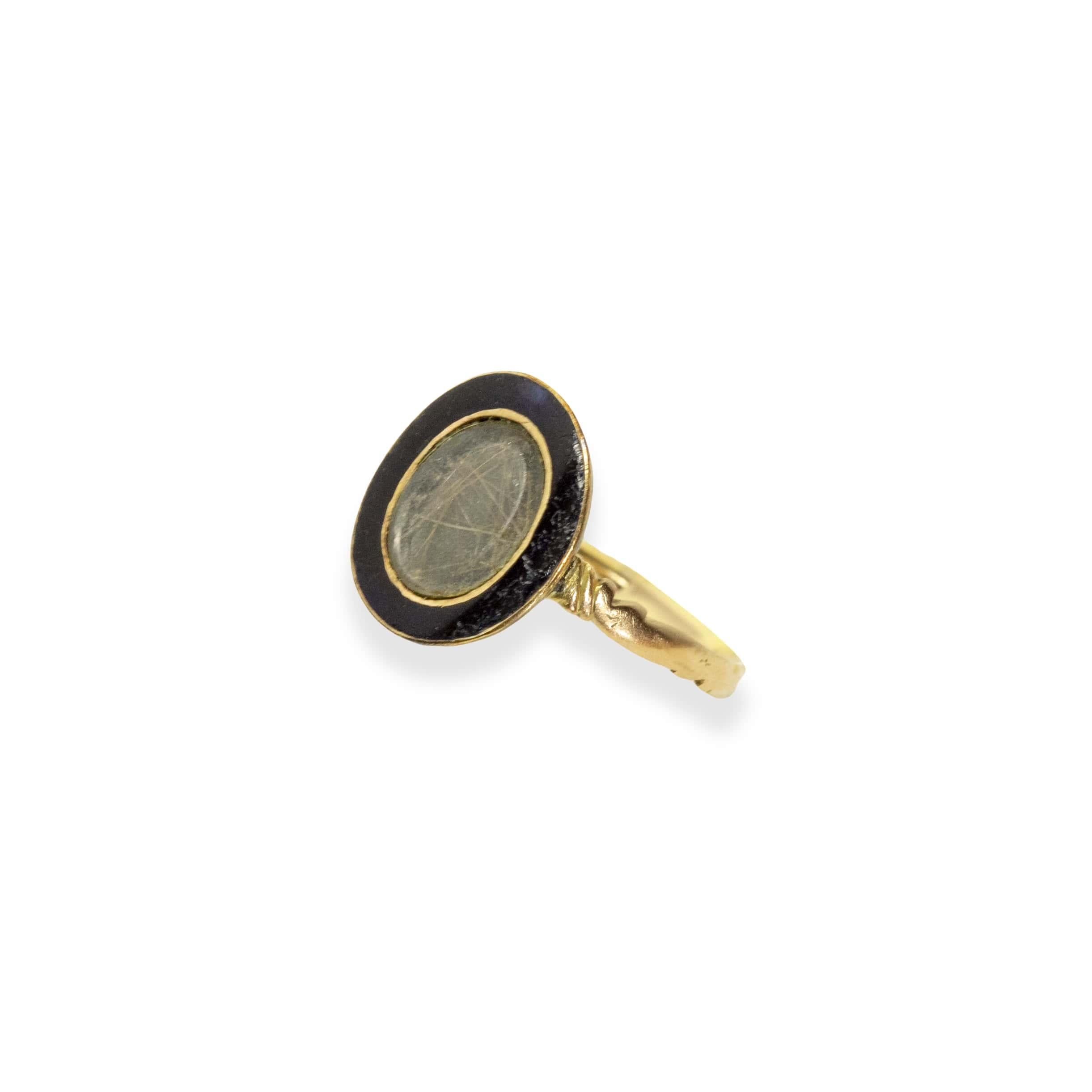 Elegant Georgian mourning ring set in 18k gold. The oval head is set in funereal black enamel which morphs into a very dark blue in strong sunlight. Which surrounds a crystal hair panel with genuine hair inside. This style is quite rare. This ring