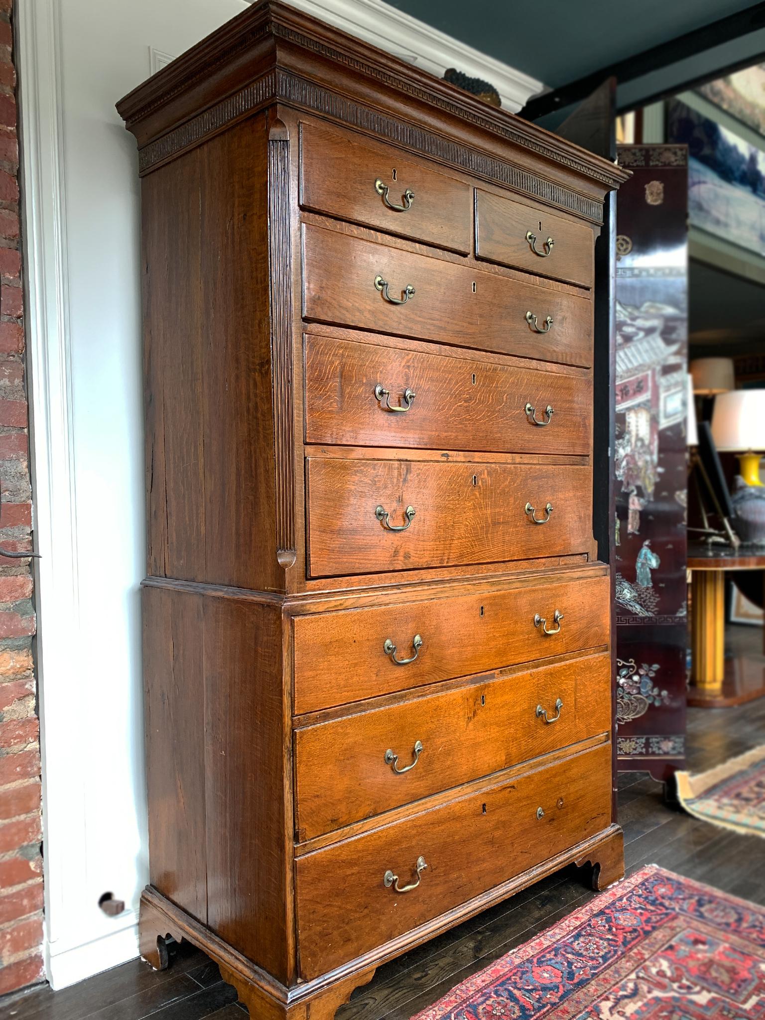 Georgian chest-on-chest handcrafted from oak in the Early 19th century. The upper chest is constructed with two small top drawers and three full-length drawers, while the bottom chest is constructed with three full-length drawers and bracket feet.