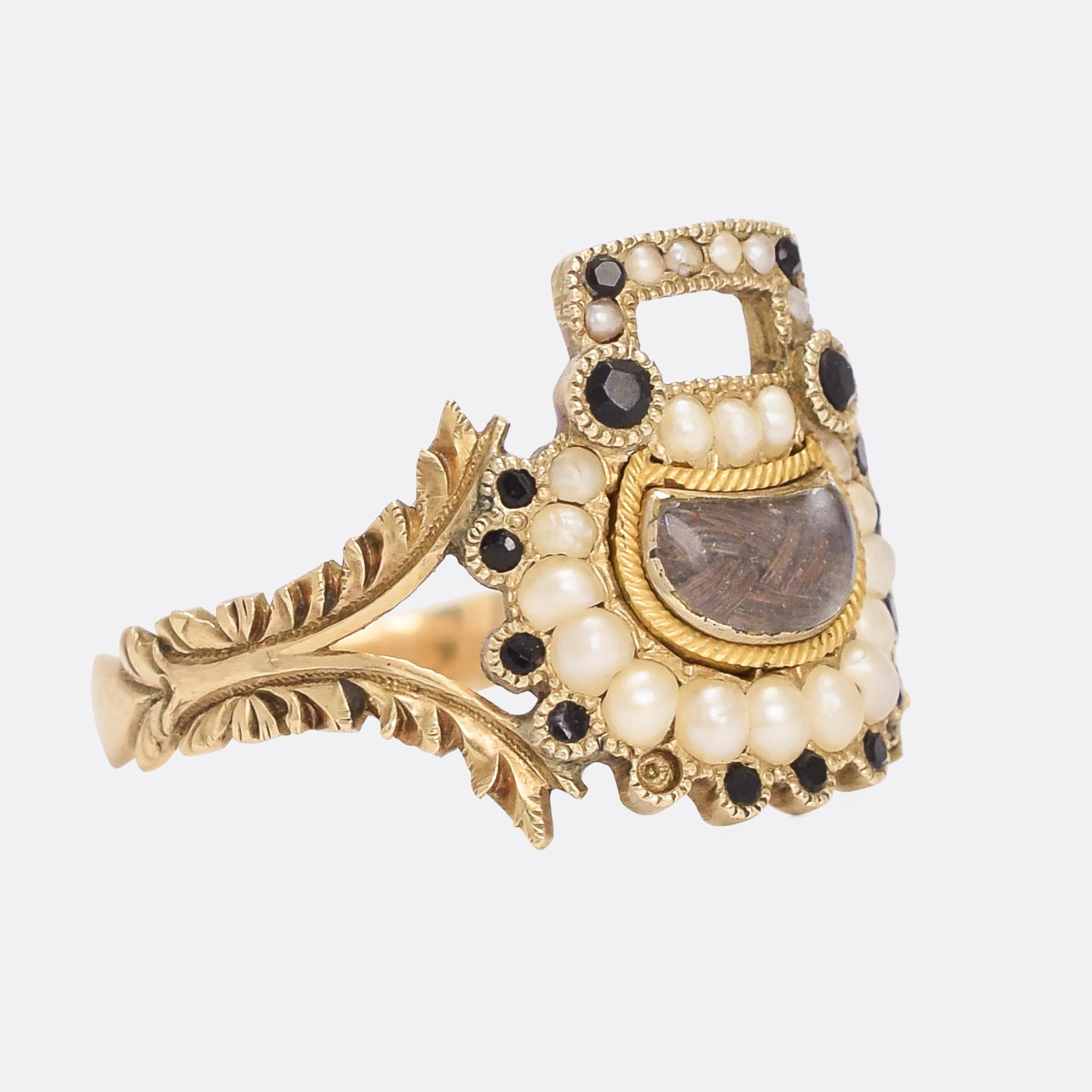 An exceptional Georgian mourning ring dating from the early 19th Century, circa 1810. The head is formed as a padlock, with a central locket compartment and studded with pearls and French jet. The elaborate split shoulders are adorned with foliate