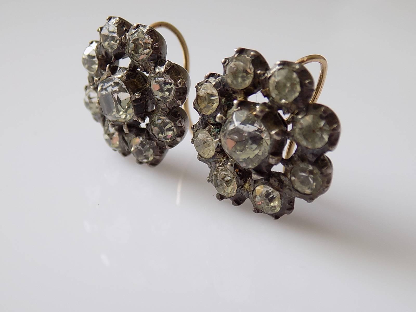 An Antique Georgian c.1800 cushion and round cut Paste cluster earrings for pierced ears. The foil backed paste in close back solid silver setting with a yellow gold hooks. English Origin.
Width 18mm.
Weight 9.2gr.
Unmarked.