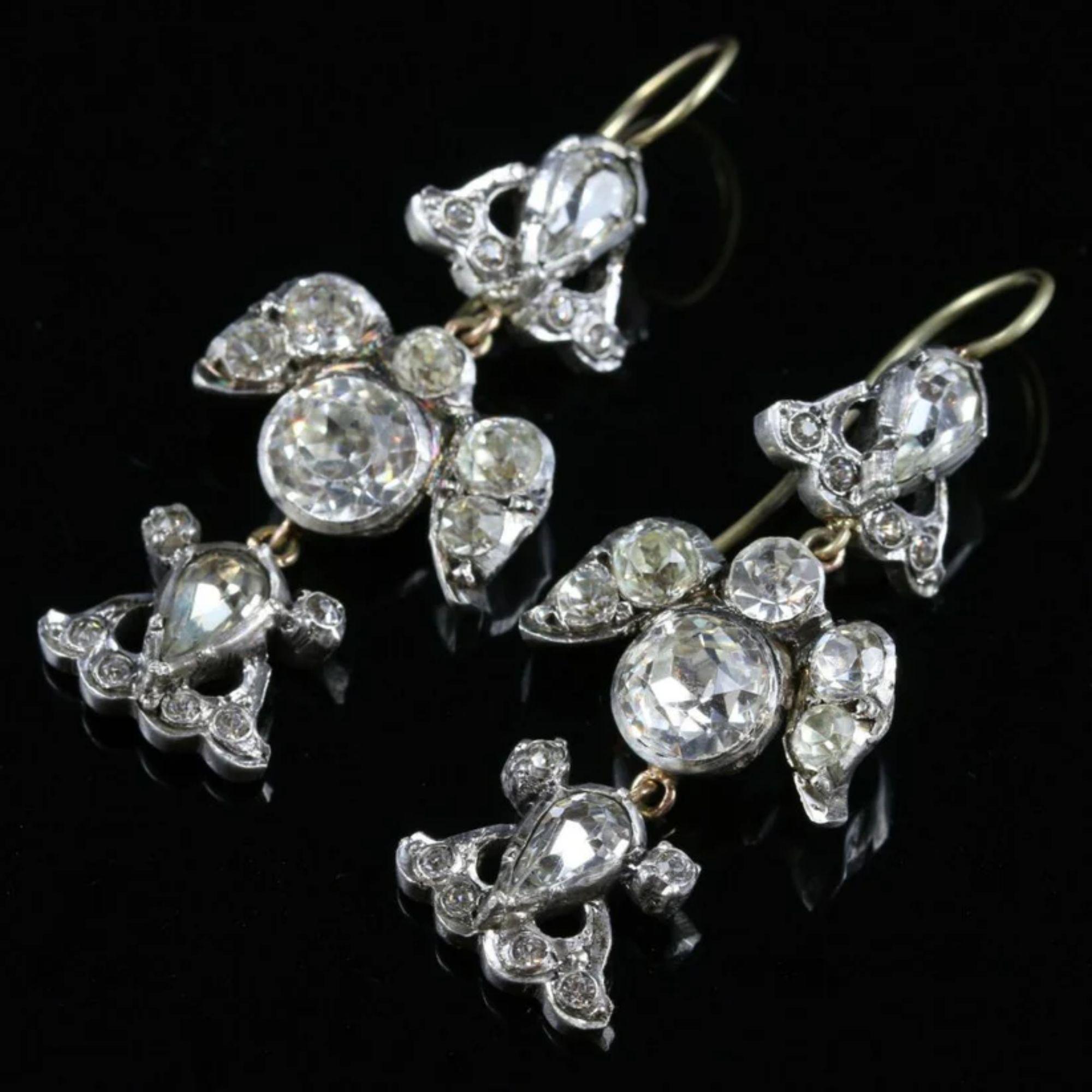 A fabulous pair of antique Georgian drop earrings from the early 1800s decorated with glistening old mine and pear cut paste stones collet set in fancy galleries that together resemble two birds.

Paste is a transparent flint glass that is cut to