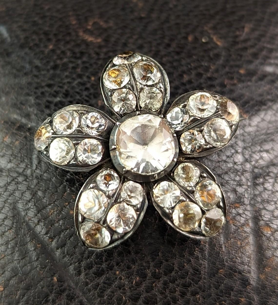 This antique Georgian foiled back paste lace pin is so unusual and alluring.

Made from sterling silver it is designed as a flower head and is set with sparkling clear paste stones.

This was most likely a lace or fichu pin based on its size, used