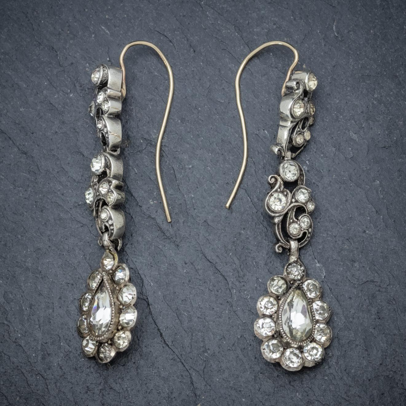 A fabulous pair of antique Georgian double drop earrings decorated with sparkling clear Paste stones across the length with a stunning teardrop shaped stone at the bottom.  

The ornate galleries are modelled in strong Silver and fitted with 18ct