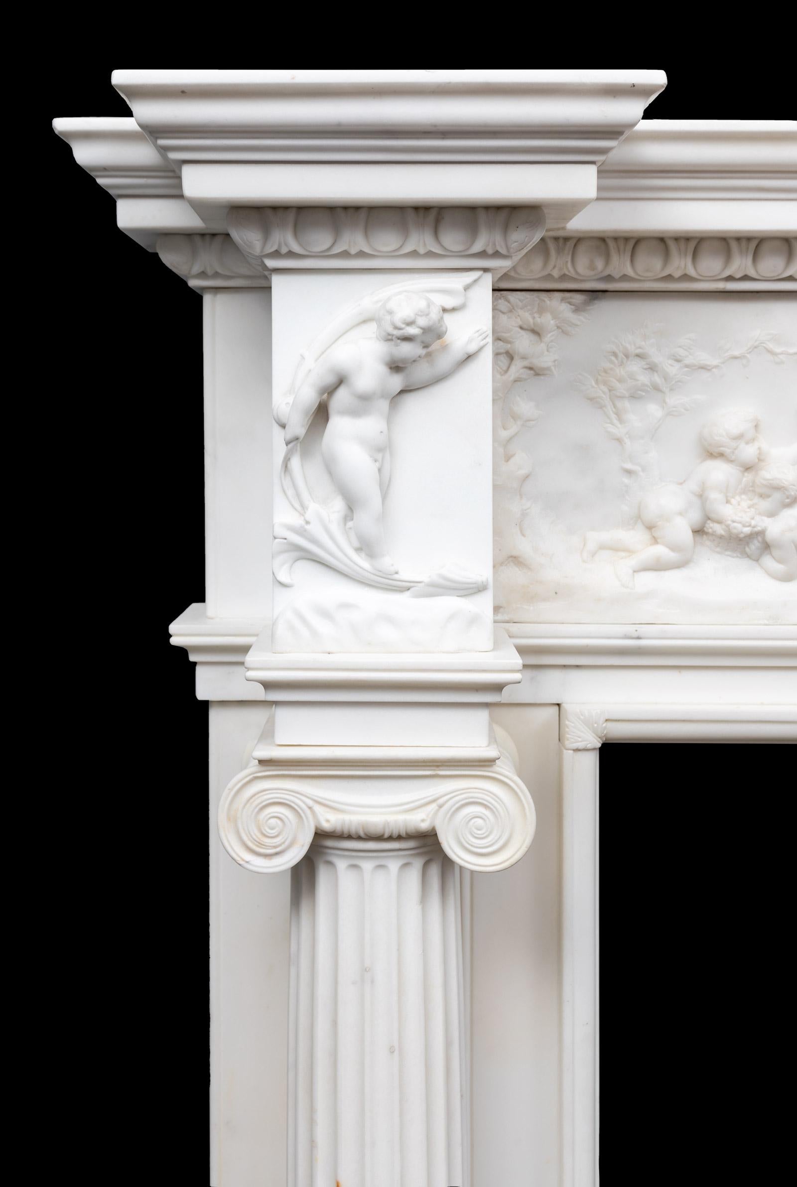 An exceptional antique carved white statuary marble chimneypiece from the late Georgian period.
With full free standing and fluted ionic columns under carved putti corner blocks. A substantial egg and dart cornice shelf rests on a finely carved
