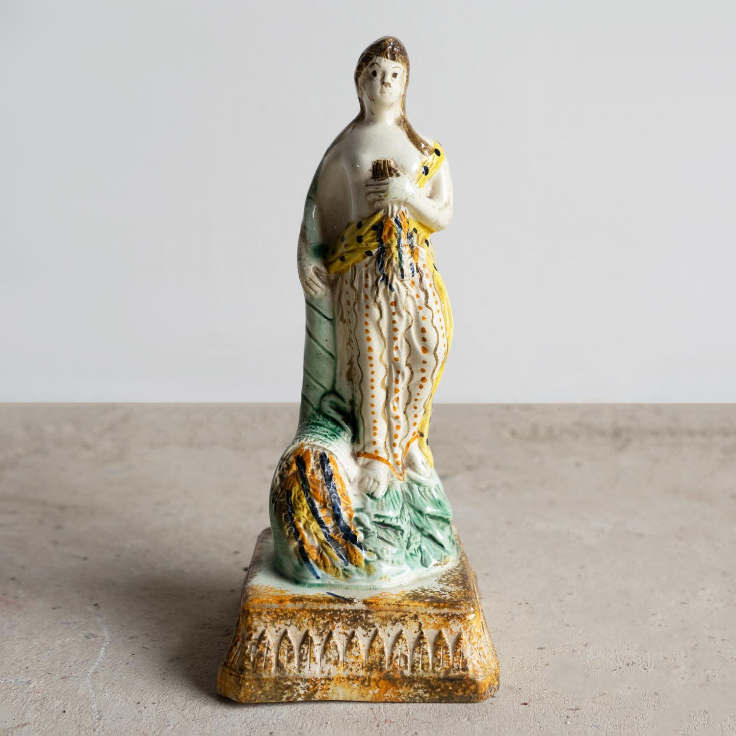 ANTICA STATUETTA INGLESE IN CERAMICA

Una figura meravigliosamente affascinante che raffigura la dea romana dei fiori e della primavera, Flora.

In uno stile tipicamente ingenuo con un'espressione facciale estremamente caratterizzante.

Tipica