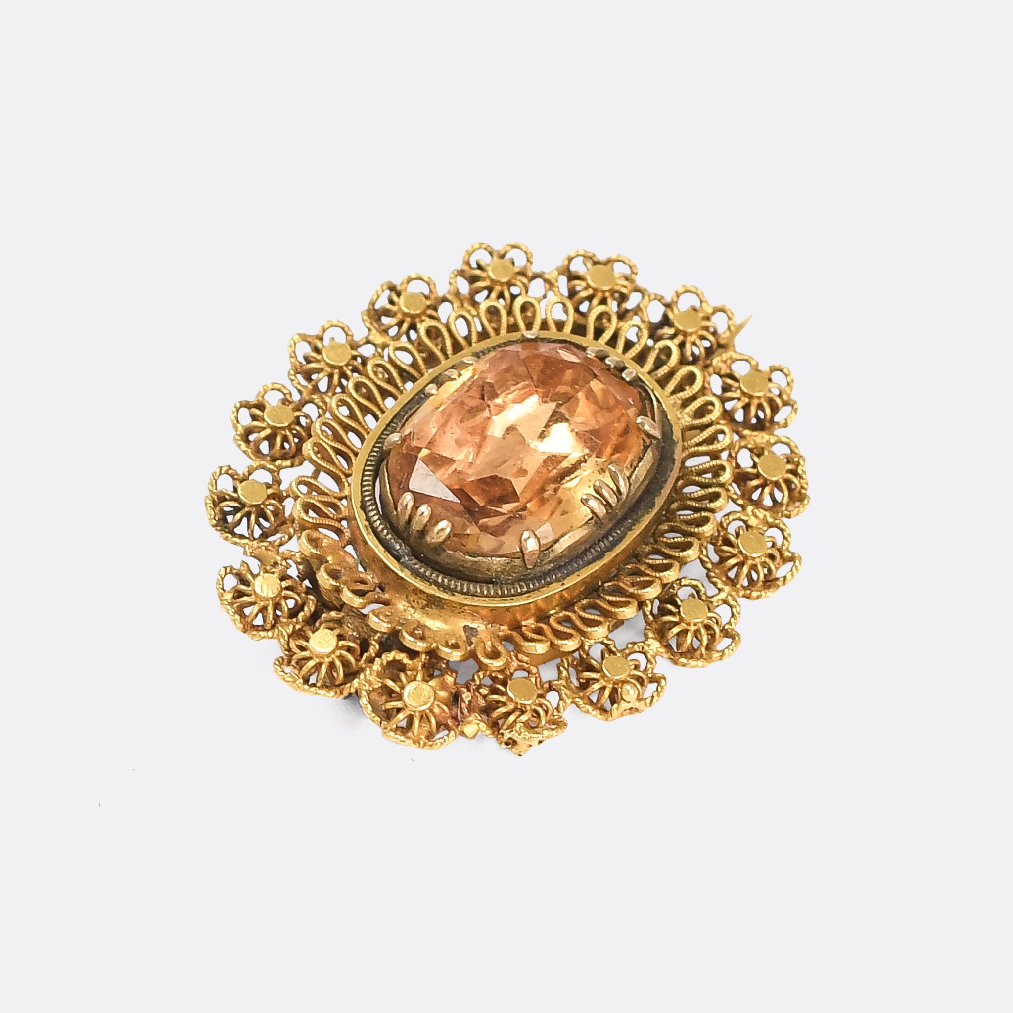 A gorgeous Georgian Regency oval brooch set with a central Imperial Topaz stone. The border is a masterclass in intricate cannetille and wirework - 15 karat gold throughout - and the stone has been set over foil to further enhance it's