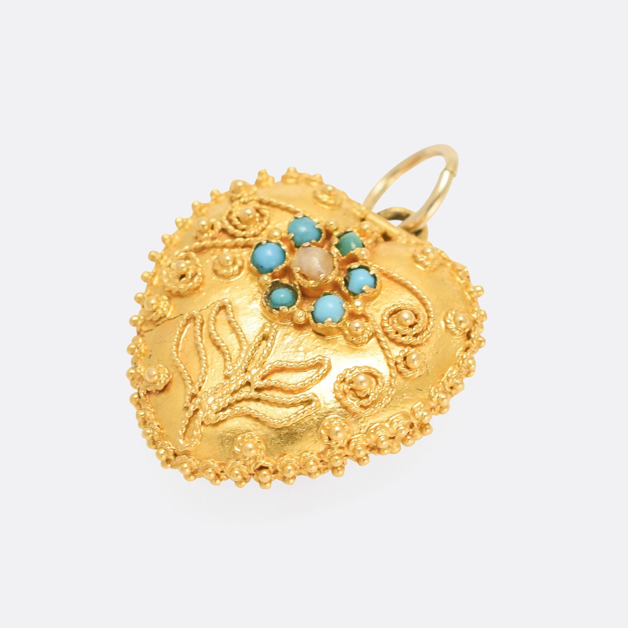 A beautiful Georgian heart locket dating from the English Regency period, circa 1810. It's adorned with a turquoise and pearl forget-me-not flower, along with intricate applied rope and pommel goldwork. Hinged at the top, it opens to reveal a