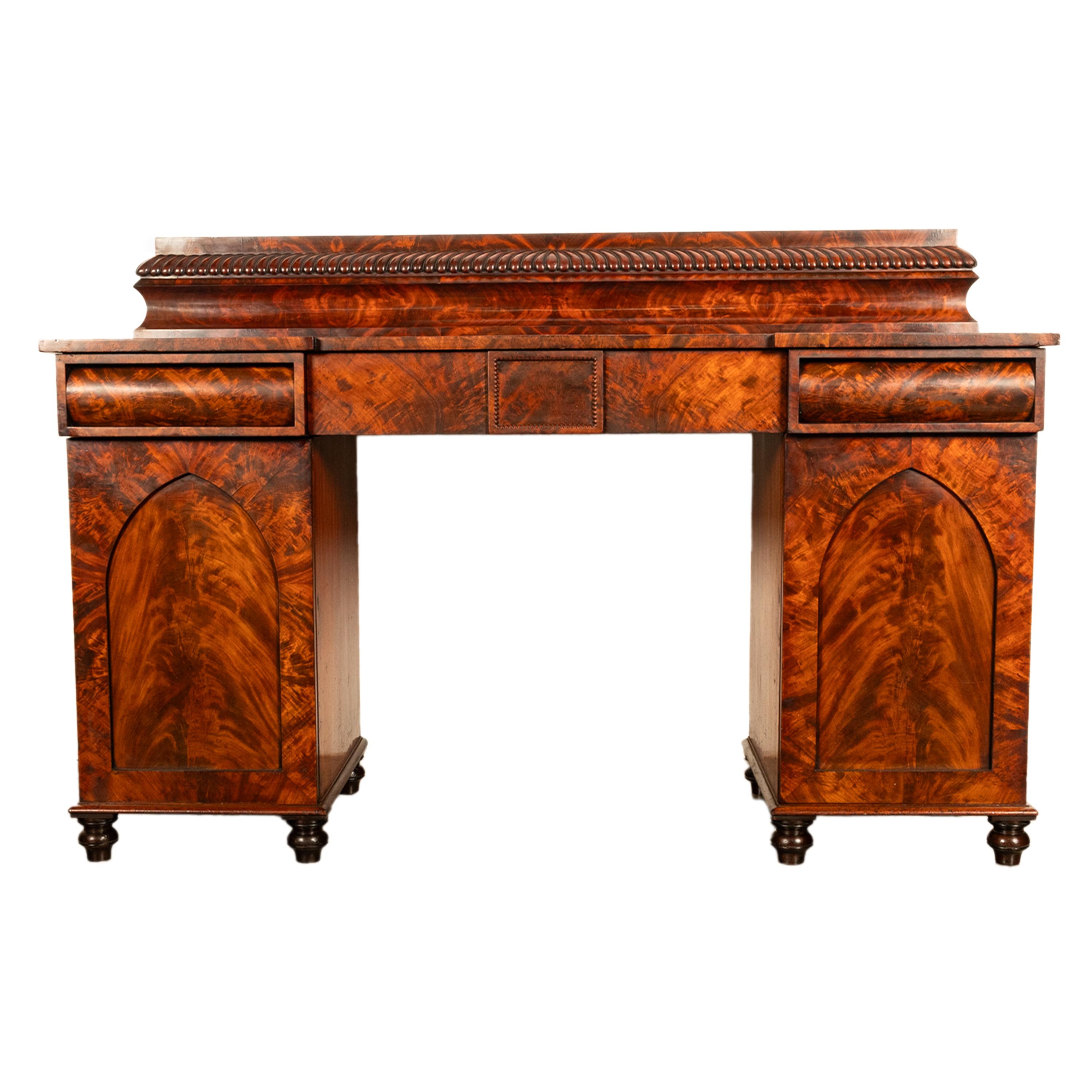 A very elegant antique late Regency flame mahogany twin pedestal sideboard, circa 1825.
The sideboard/server with a galleried back having a band of carved gadrooned decoration, the base is of inverted breakfront form with three drawers. The central