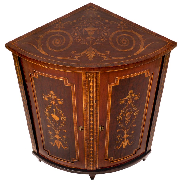 A spectacular antique Georgian marquetry bowfronted Regency period corner cabinet in the Neoclassical style, circa 1800.
The cabinet is profusely and sumptuously inlaid with specimen fruitwoods, rosewood and satinwood, the top having scrolling