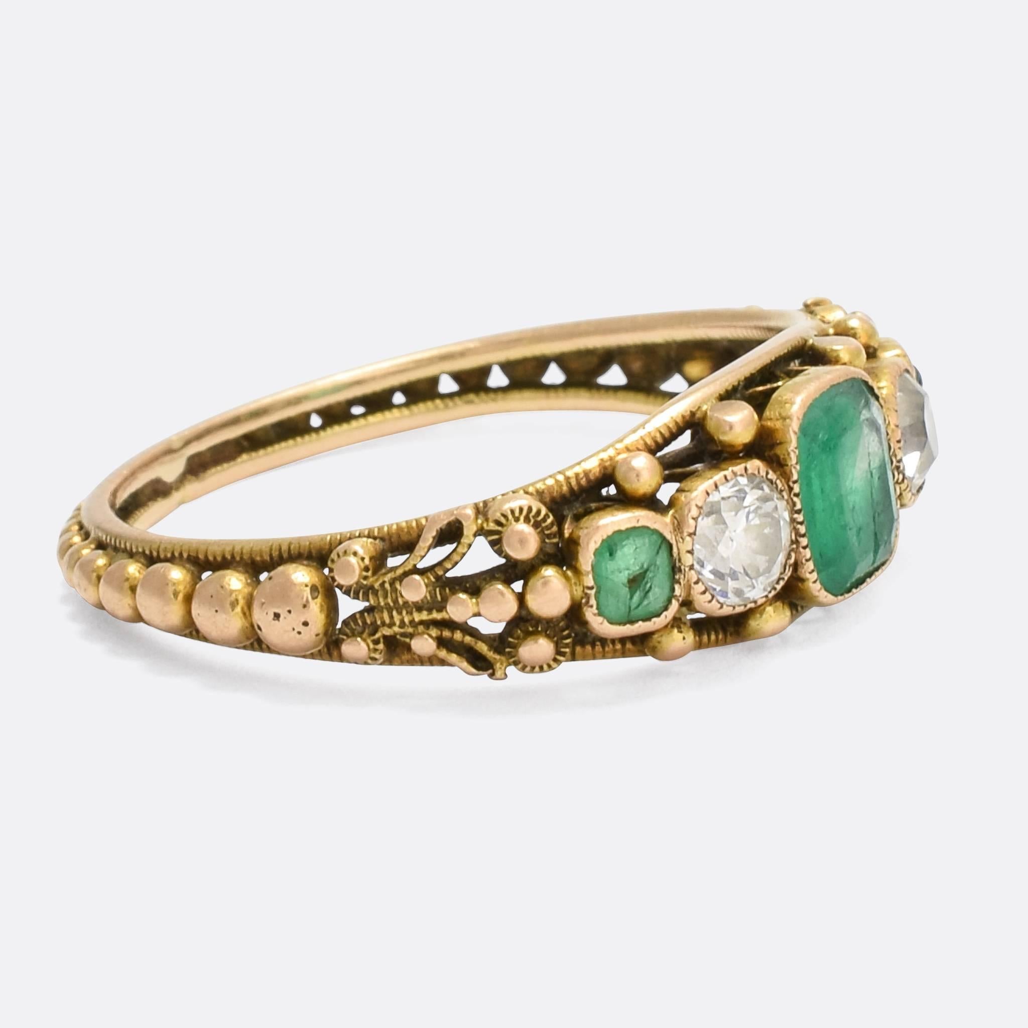 A stunning Georgian Regency Period five-stone ring set with natural emeralds and old mine cut diamonds. The craftsmanship is exceptional, with applied filigree detailing and graduated pommels around the band. Modelled in 15k gold throughout, it