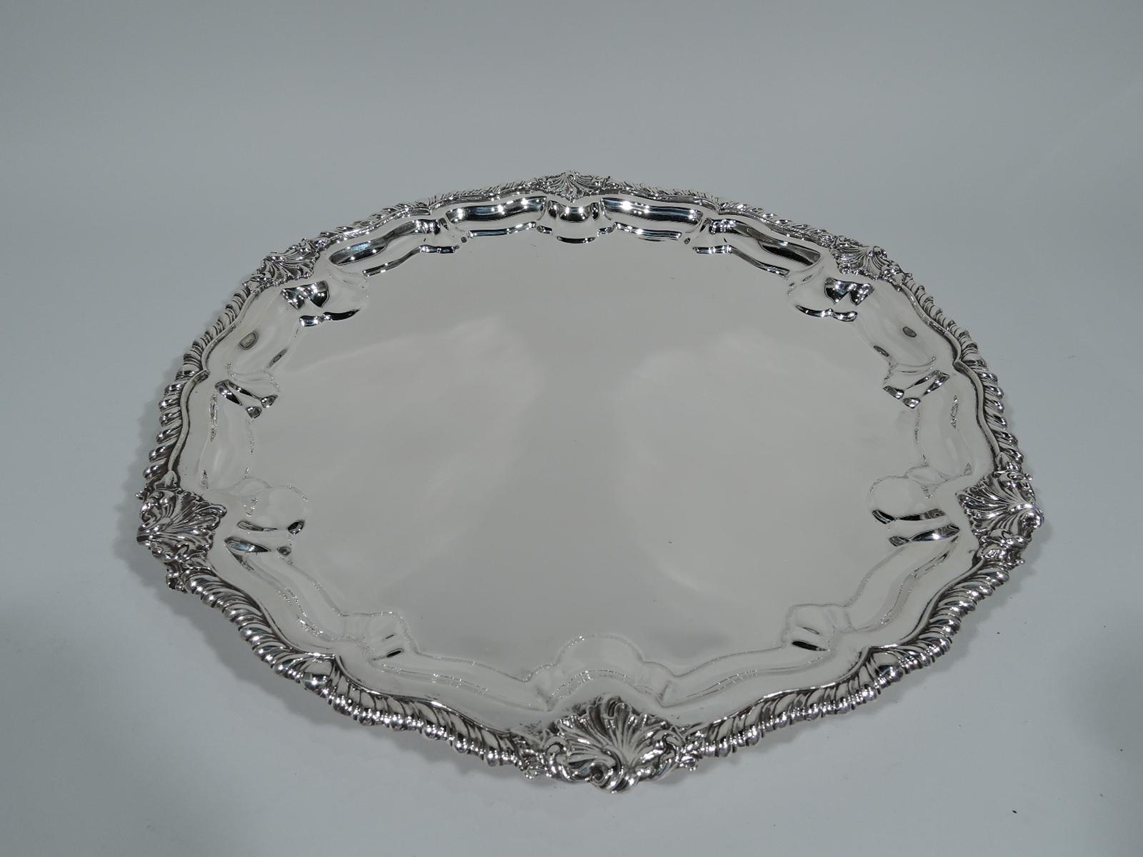 Georgian Revival sterling silver salver. Made by Howard & Co. in New York in 1905. Round with gently scrolled and gadrooned rim interspersed with scallop shells. Rests on three scallop shells supports. A beautiful piece in the traditional style.