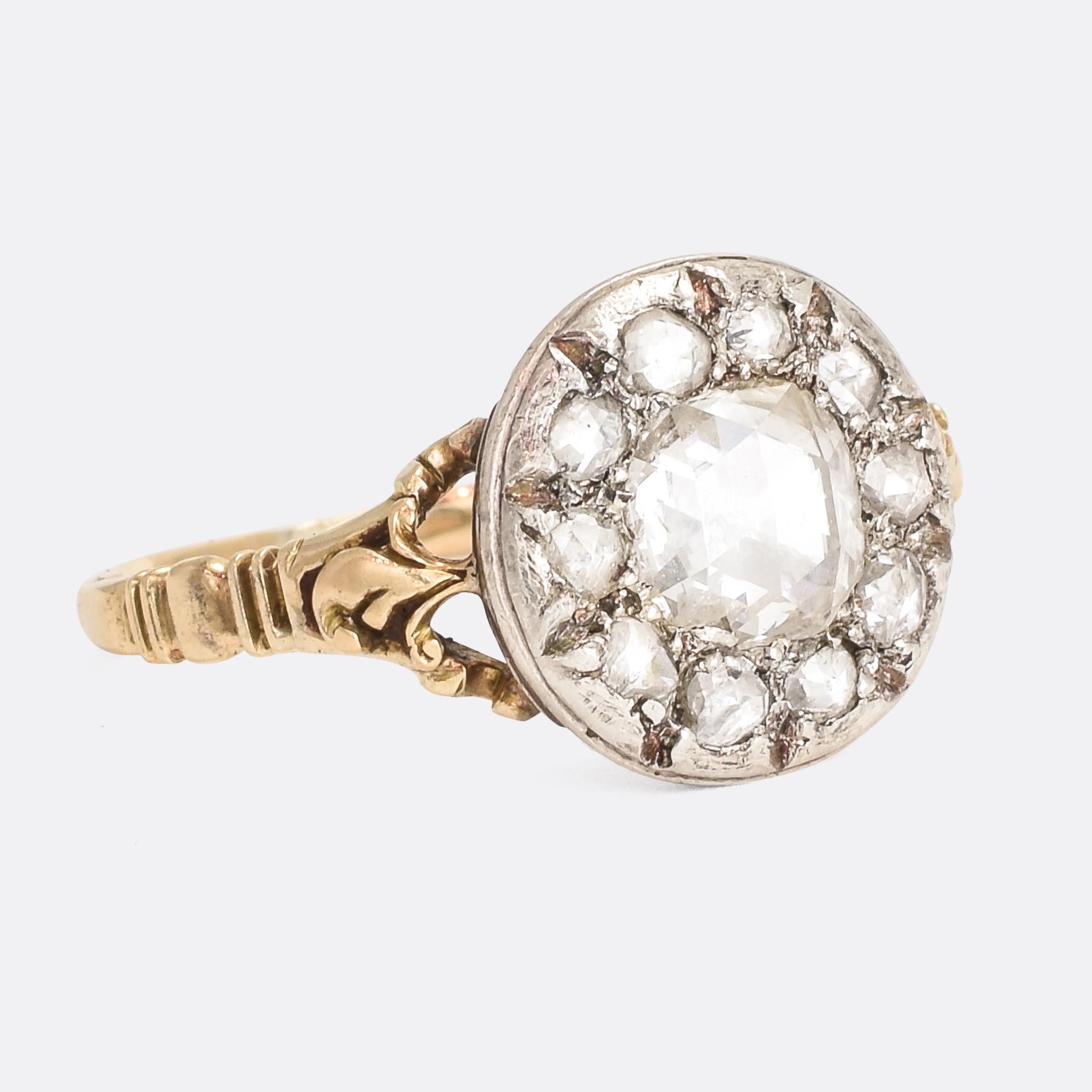 A wonderful antique Georgian cluster ring set with rose cut diamonds. The central stone spreads around one carat, surrounded by a halo of smaller diamonds. It dates to the latter half of the 18th Century; with fluted design to the back of the head,