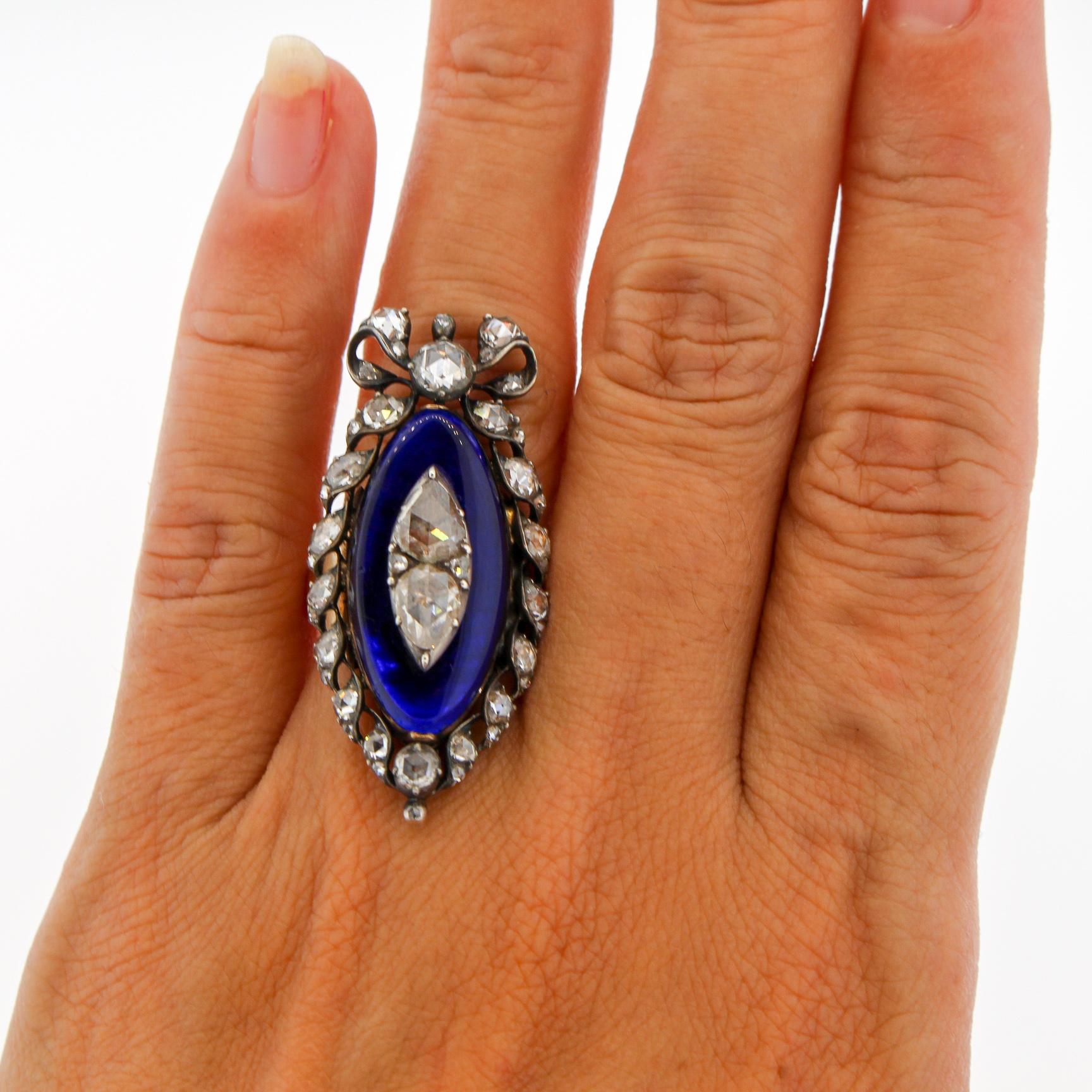 A bold silver and gold blue glass navette shaped rosecut diamond Georgian ring circa 1820. The ring is bright blue glass surrounded by a ribbon of rosecut diamonds and a bow at the top. The ring is set with 43 various shaped rosecut diamonds