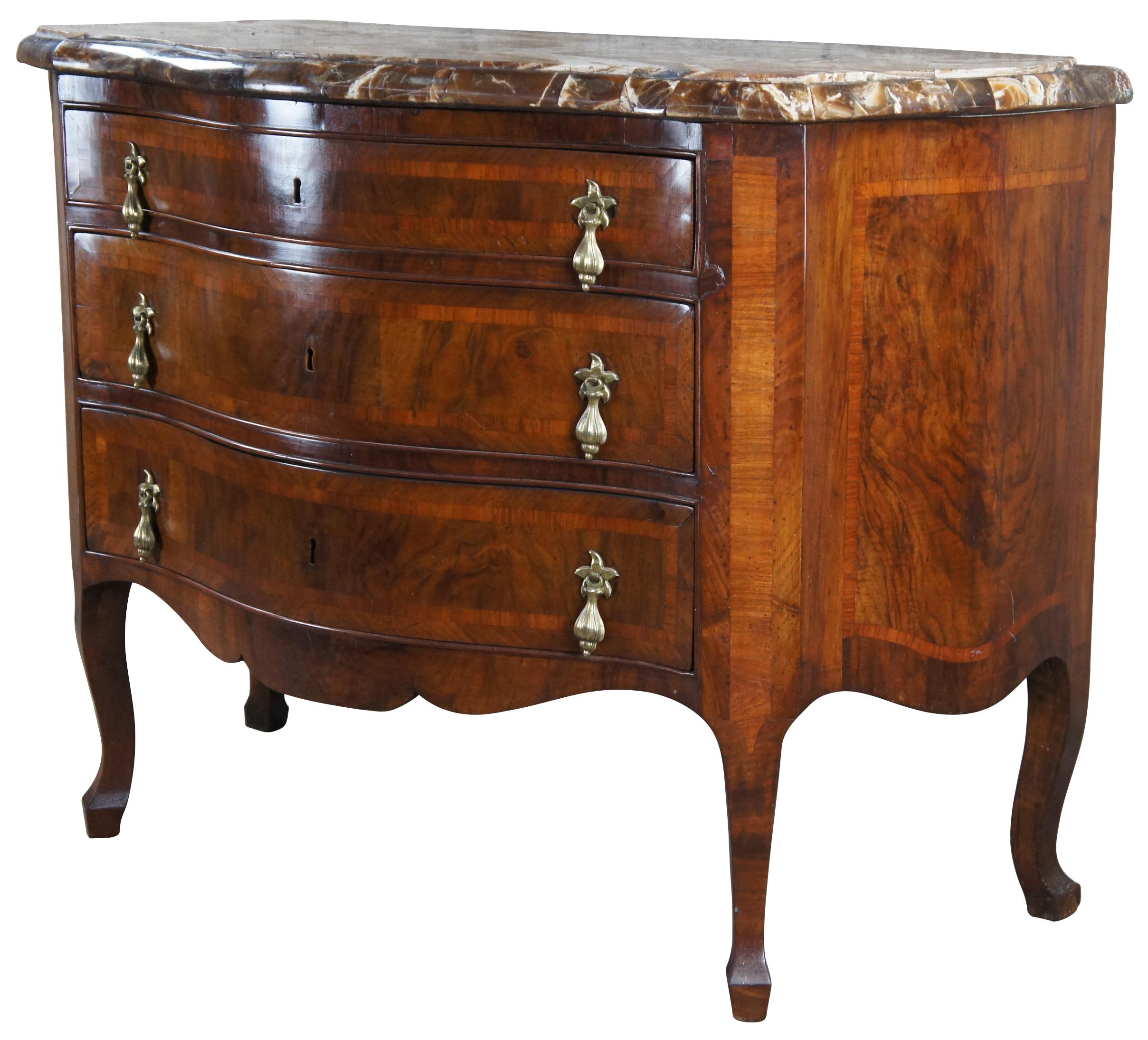 An exquisite late 18th / early 19th century commode. Made from mahogany with an oxbow form featuring cross banding walnut and burled panels. Includes three hand dovetailed drawers with brass dangle pulls. The case is supported by square tapered legs.